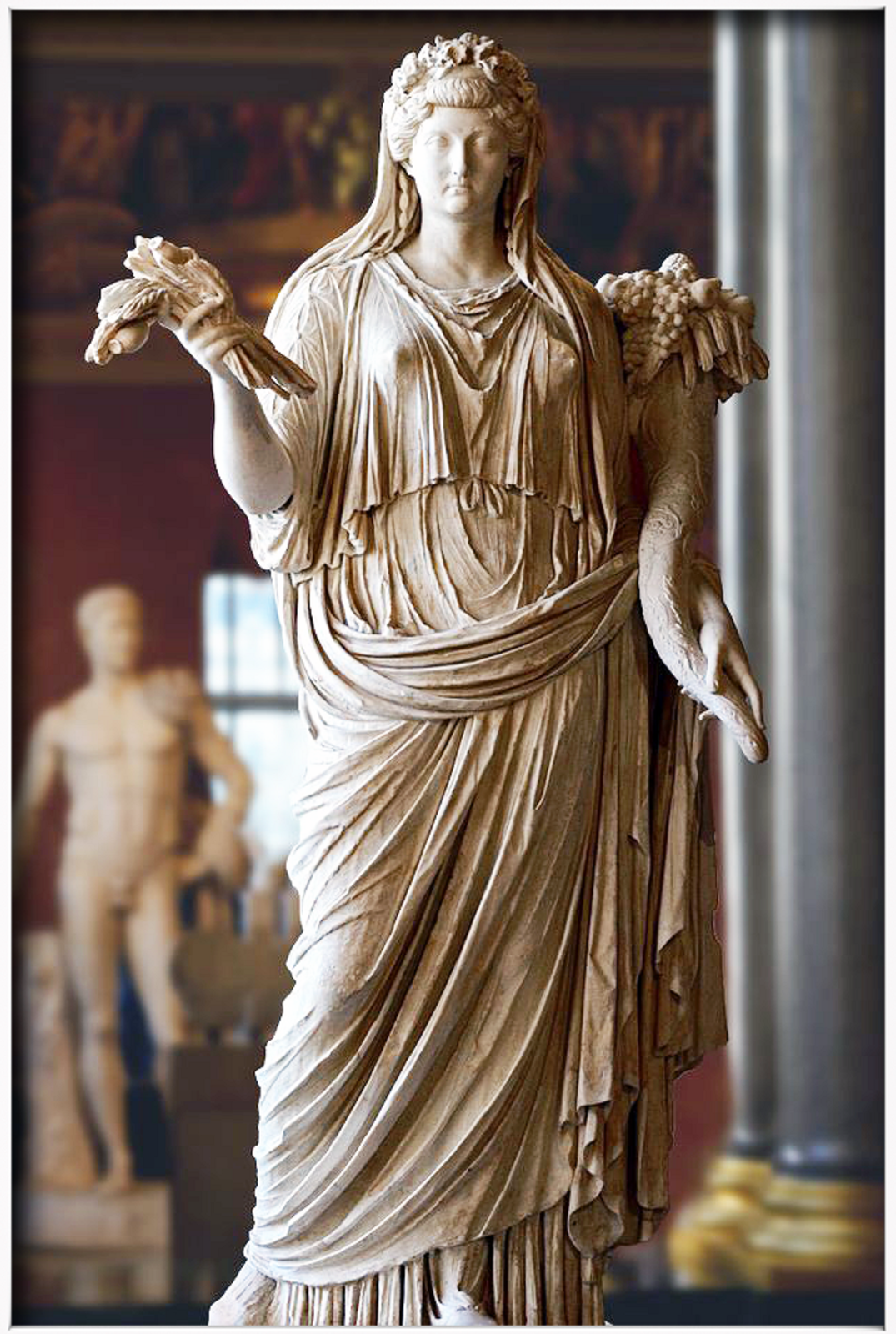 Ilustracja przedstawia rzeźbę „Bogini Demeter”. Rzeźba ukazuje kobietę w długiej szacie. Postać w lewej dłoni trzyma kłosy zbóż, w prawej zaś róg obfitości. Kobieta pewnie spogląda przed siebie.
