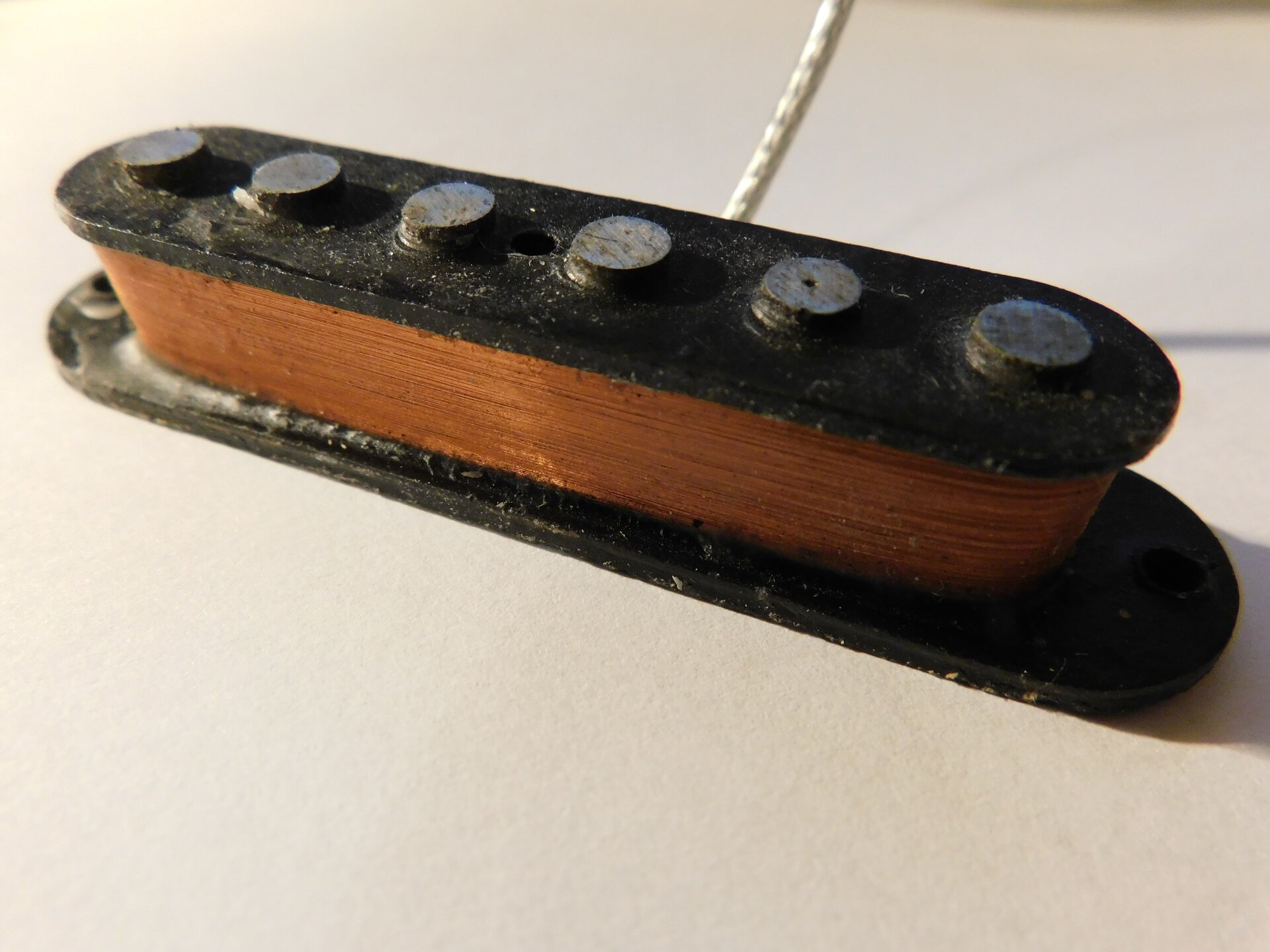 Fot. 1. Na fotografii pokazano przetwornik gitarowy pojedynczy. Sześć pionowych bolców umocowanych jest w jednej oprawie, na którą nawinięto miedziany drut.