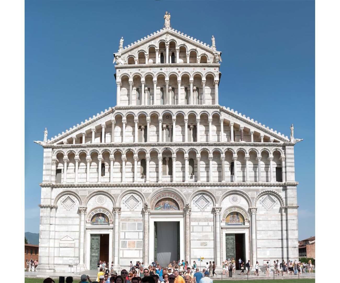 Fotografia barwna przedstawiająca Katedrę w Pizie w 1. poł. XII wieku. Wysoka konstrukcja z uwidocznionymi zewnętrznymi wyżłobieniami na elewacji. Zbudowana na kształt wieży, postawa szersza, im wyżej wzniesiona tym węższe zakończenie. Na elewacji zewnętrznej, w zagłębieniach dostrzec można namalowane obrazy.