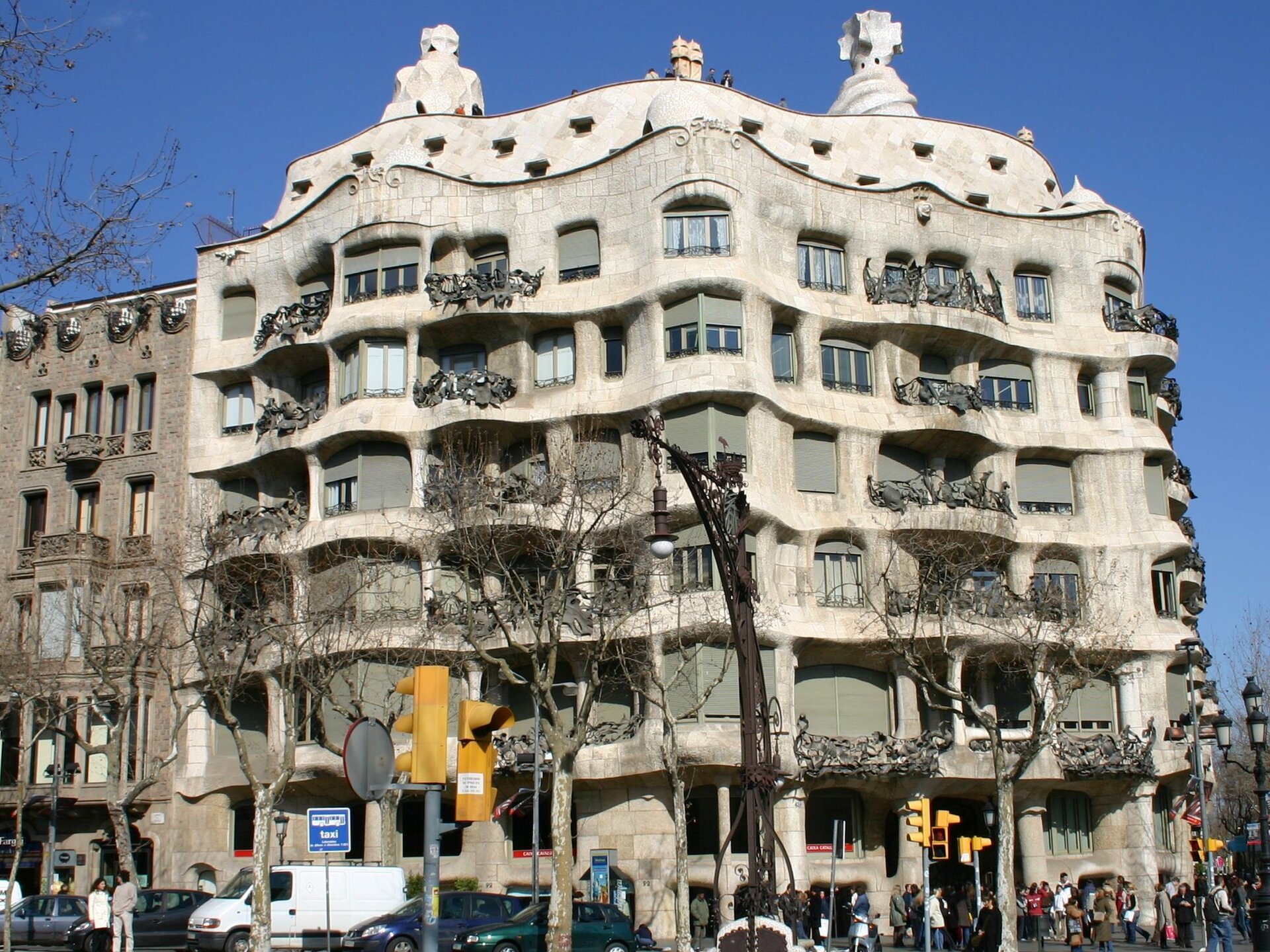 Ilustracja przedstawia budynek Casa Milà autorstwa Antonio Gaudi’ego. Fasada budynku przypomina wzburzone morze. Wygląda ciężko i monumentalnie choć wzniesiona jest z cienkich wapiennych płyt. Balkony zdobią kute z żelaza balustrady przybierające kształt dzikich chaszczy. Na elewacji budynku widnieje oryginalne zdobienie.