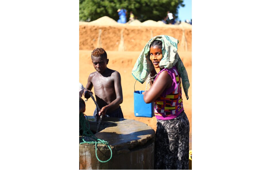 Zdjęcie przedstawia mieszkańców Madagaskaru, którzy czerpią wodę z jednej ze studni zbudowanych z fundacji charytatywnej.
