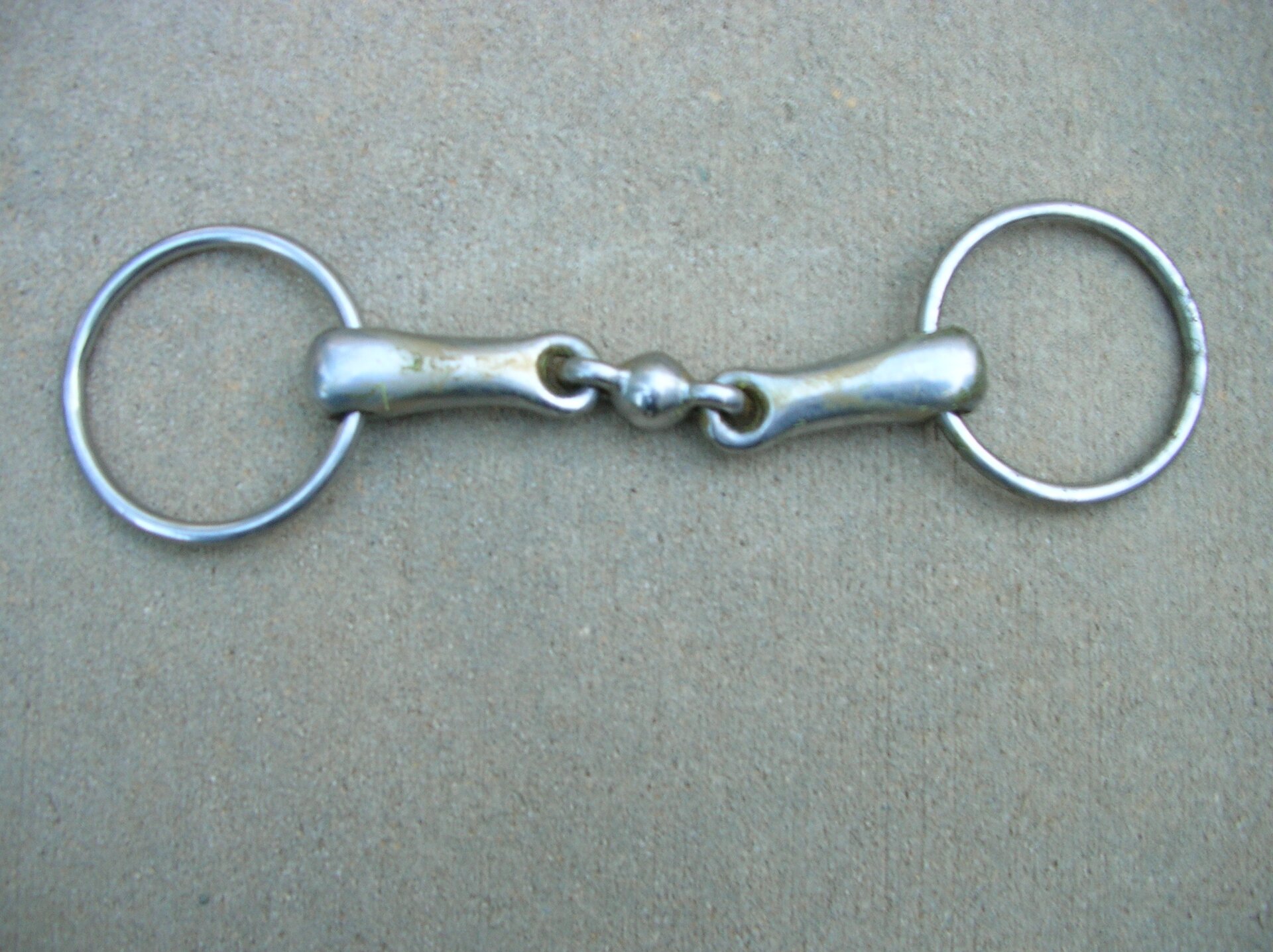 Na zdjęciu widać wędzidło podwójnie łamane. Są to dwa metalowe kółka połączone metalowym łącznikiem. Szczegółowy opis uzupełniający zdjęcie znajduje się w treści definicji.