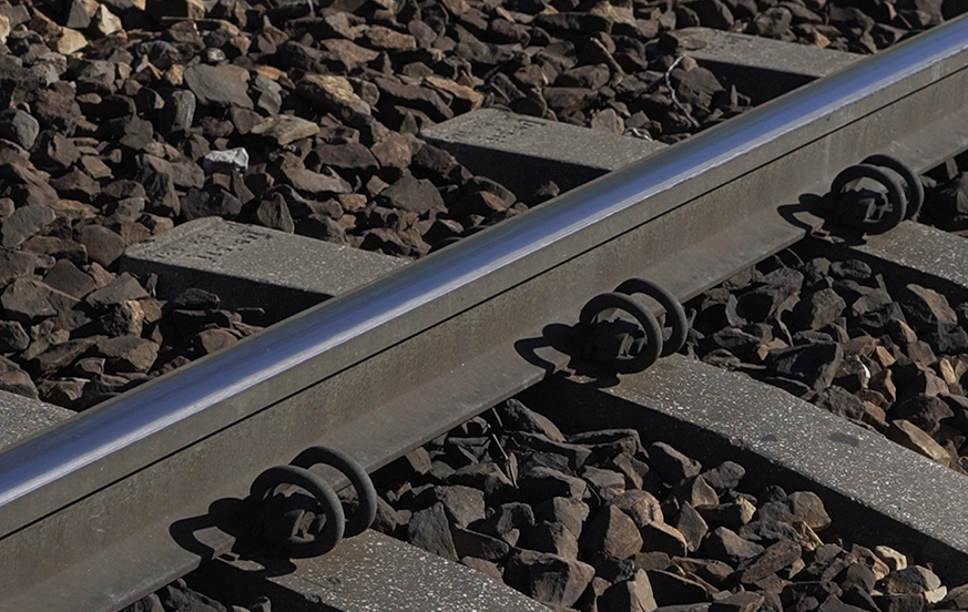 Zdjęcie przedstawia zbliżenie na tory kolejowe, a dokładniej na szynę. Dobrze widoczna jest tu główka szyny, czyli element, który bezpośrednio styka się z kołami pojazdu.