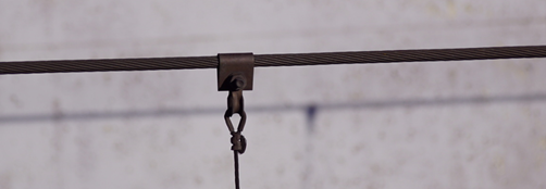 Zdjęcie pokazuje linę nośną. Jest to drut, który rozwiesza się między podporami. Widoczny jest tutaj górny koniec wieszaka do podwieszania drutu jezdnego.