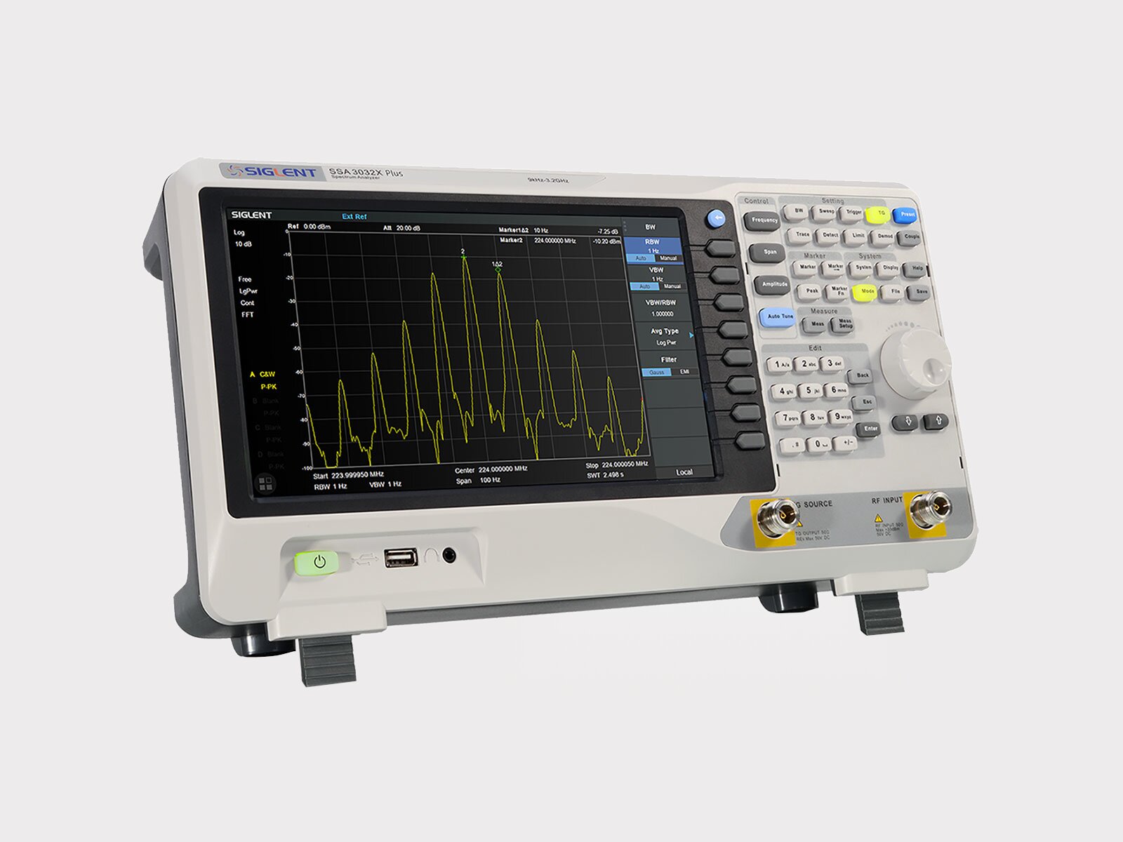 Ilustracja przedstawia urządzenie o prostokątnym froncie. Na froncie znajduje się duży ekran, wyświetlony jest na nim wykres. Po prawej stronie widać rządy przycisków oraz pokrętło. Poniżej znajduje się przycisk włączania i wyłączania oraz miejsce na wtyk.