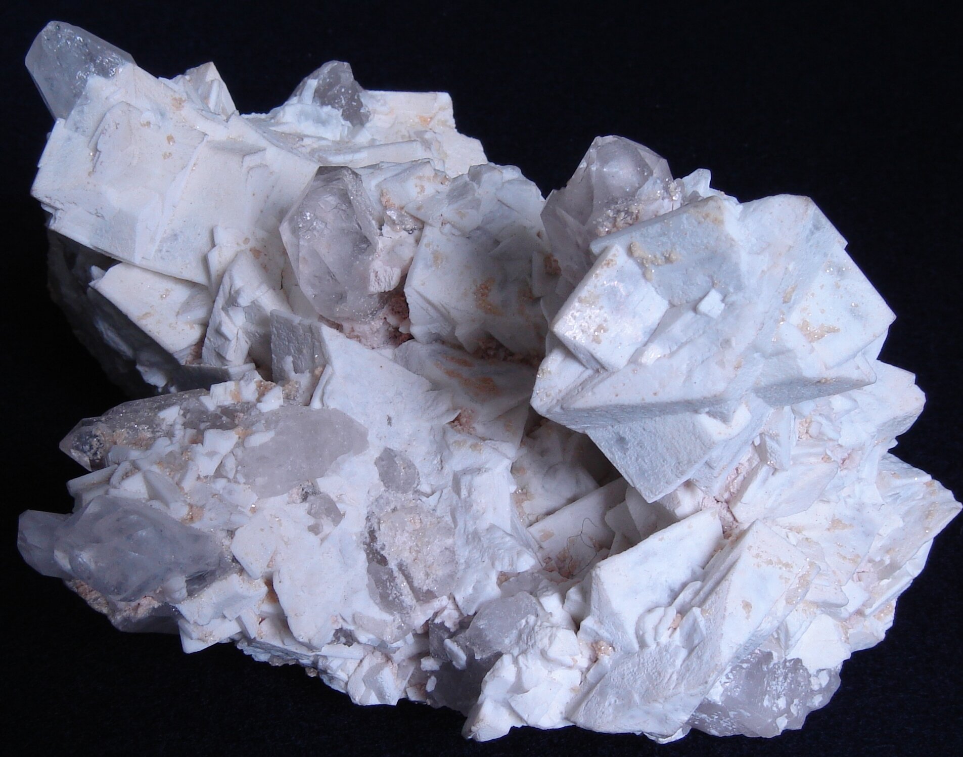 Zdjęcie przedstawia biały minerał zbudowany z tabliczek połączonych ze sobą w różnych kierunkach. 