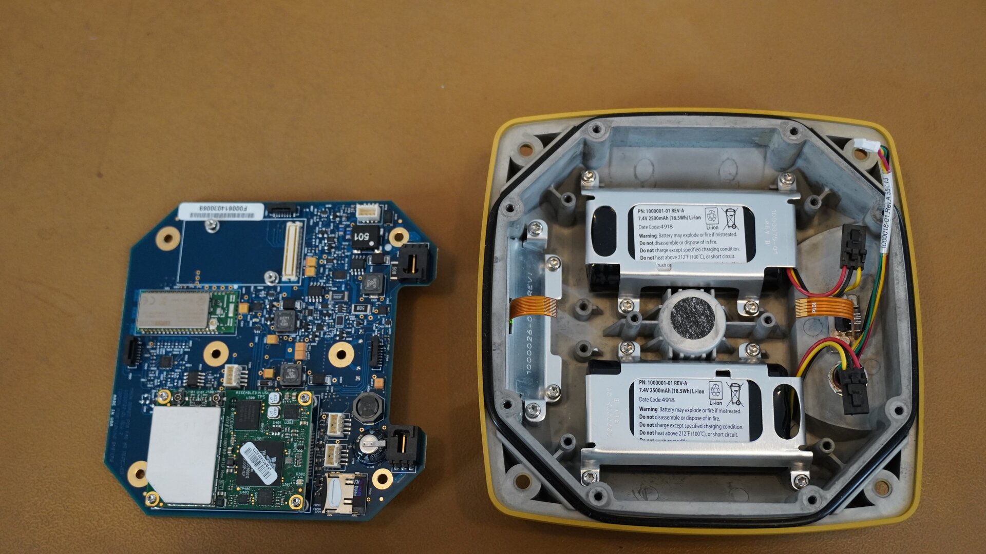 Na zdjęciu przedstawiono wnętrze odbiornika GNSS po odsłonięciu płyty głównej. W dolnej części obudowy widoczne są dwie baterie oraz złącza modułu. Po lewej stronie widać płytę główną.