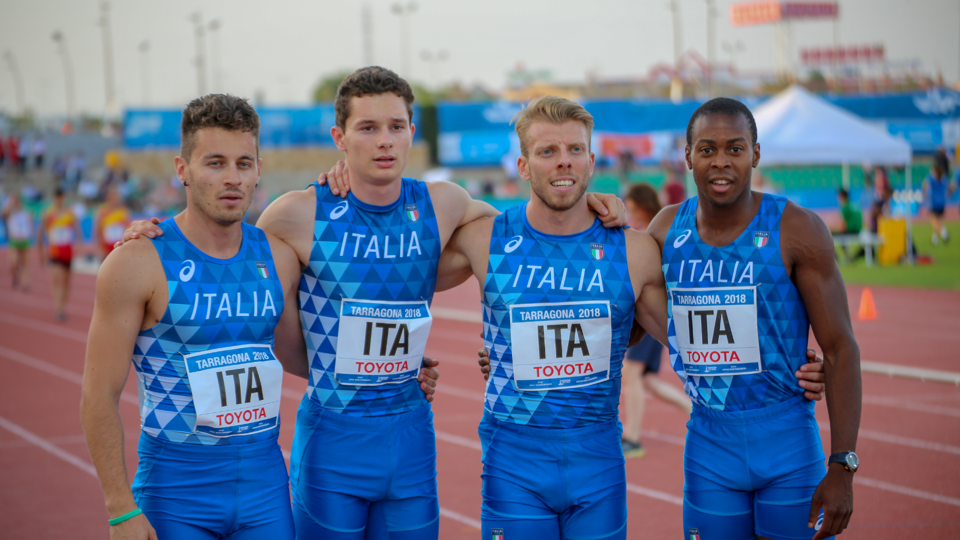 Zdjęcie przedstawia czterech mężczyzn w sportowych strojach do biegania, którzy tworzą drużynę reprezentacji Włoch w sztafecie.
