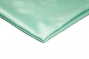 Zdjęcie ukazuje próbkę tkaniny atłasowej w seledynowym kolorze.