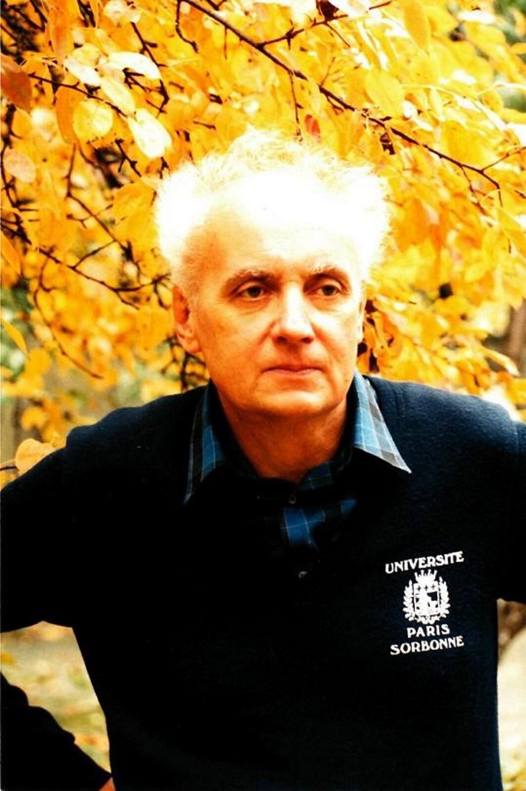 Fotografia przedstawia Wojciecha Kilara, która została wykonana przez fotografa Andrzeja Klukowskiego wczesną jesinną. Postać ma siwe włosy, ma wpatrzoną i zamyśloną twarz. Ubrany jest w koszulę w kratkę i niebieski sweter z logo po lewej stronie: UNIVERSITE PARIS SORBONNE.