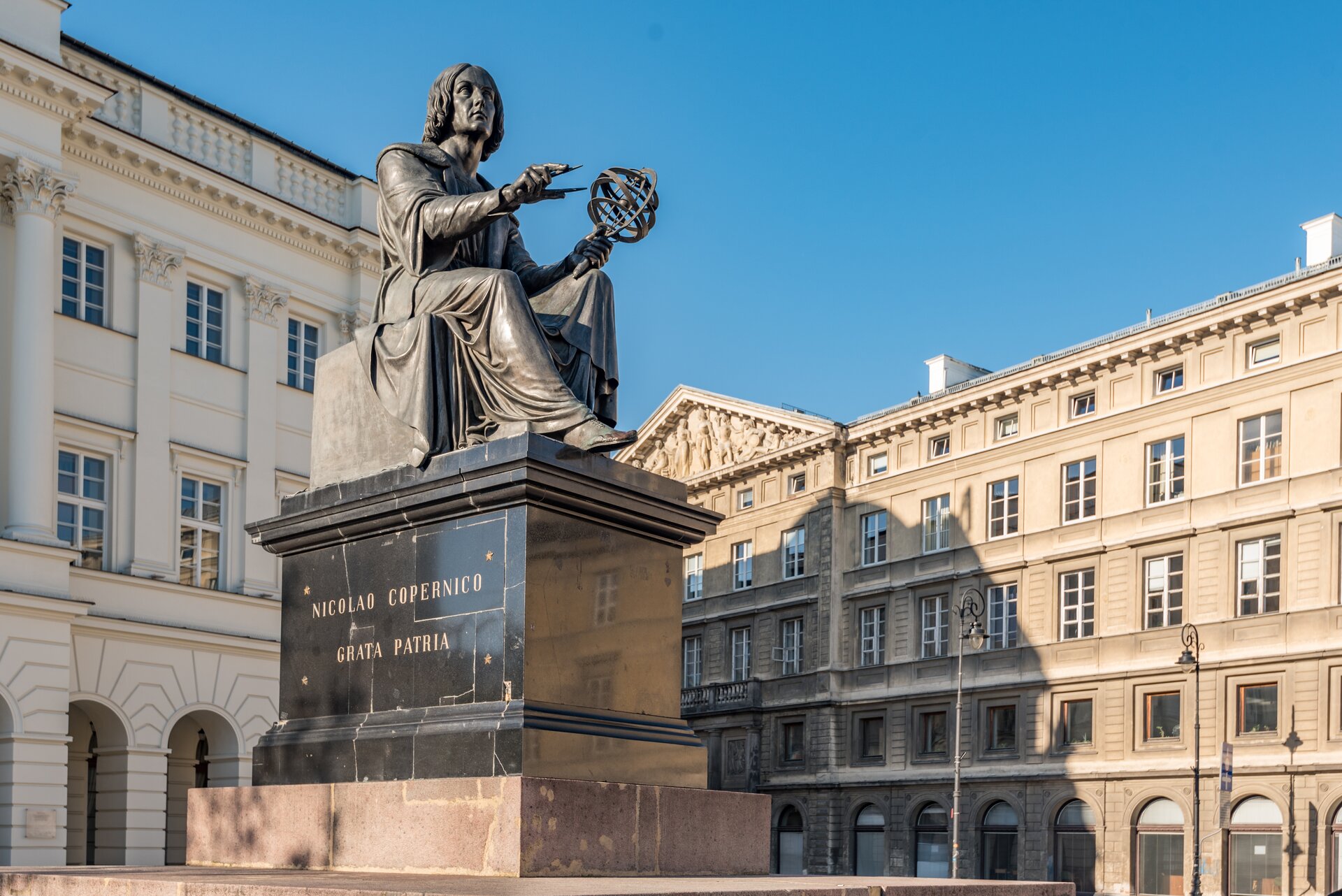 Fotografia nieznanego autorstwa przedstawia pomnik Mikołaja Kopernika dłuta Bertela Thorvaldsena. Kopernik został przedstawiony jako mężczyzna w średnim wieku, ma długie włosy sięgające do ramion, ubrany jest w długie szaty, w dłoniach trzyma narzędzie do pomiarów oraz cyrkiel. Na cokole pomnika widnieje napis: NICOLAO COPERNICO GRATA PARTIA