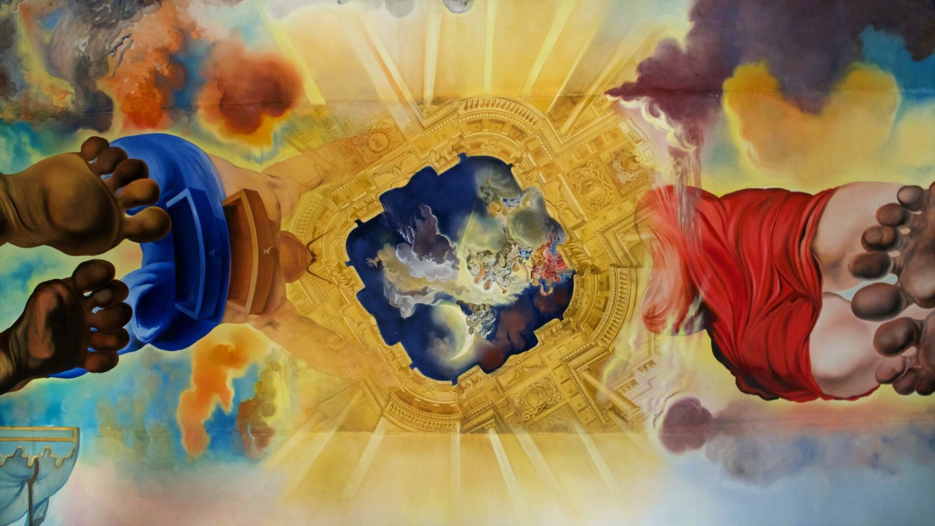 Fotografia przedstawia dekorację sufitu w Muzeum i Teatru Dalego [czytaj: dalego] w Hiszpanii. Ukazane są od dołu dwie postaci: mężczyzna w niebieskich spodniach i kobieta w czerwonej sukience. Podtrzymują rękoma namalowane na suficie złote obramowanie, w środku którego przedstawione zostało nocne niebo z sierpem księżyca i kolorowymi chmurami.