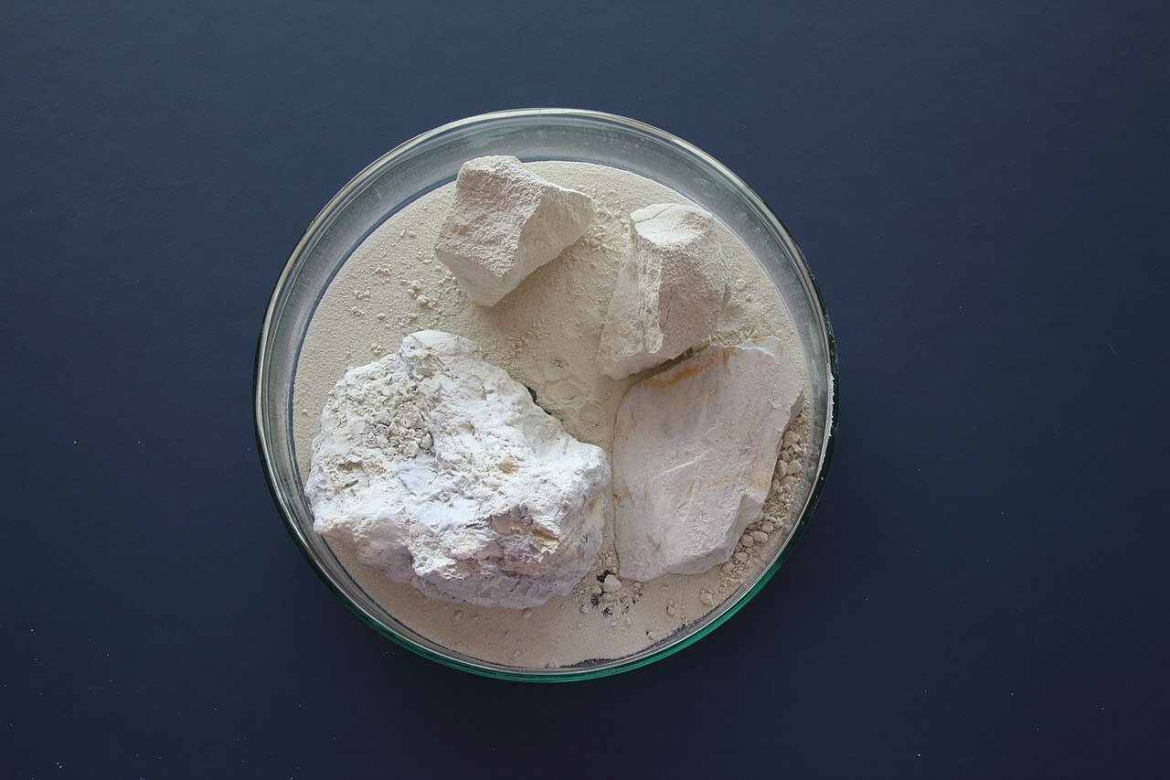Zdjęcie przedstawiające kaolin. Biały minerał w postaci zbitego proszku ułożony jest na szalce Petriego.