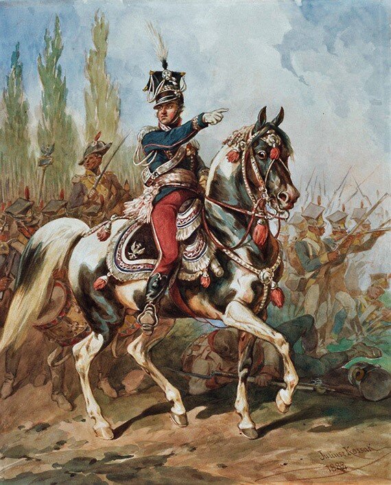 Ilustracja przedstawia generała Jana Henryka Dąbrowskiego na czele Legionów. Dowódca jedzie konno, ubrany jest w wojskowy mundur, wskazuje kierunek wojsku w który ma uderzyć. 