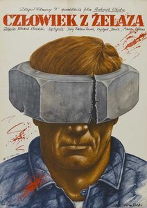 Zdjęcie przedstawia plakat filmu Człowiek z żelaza. Jest na nim głowa mężczyzny. Na głowie ma założoną metalową nakrętkę, w ten sposób że zasłania ona czoło i oczy. W jednym miejscu nakrętka jest pęknięta.  