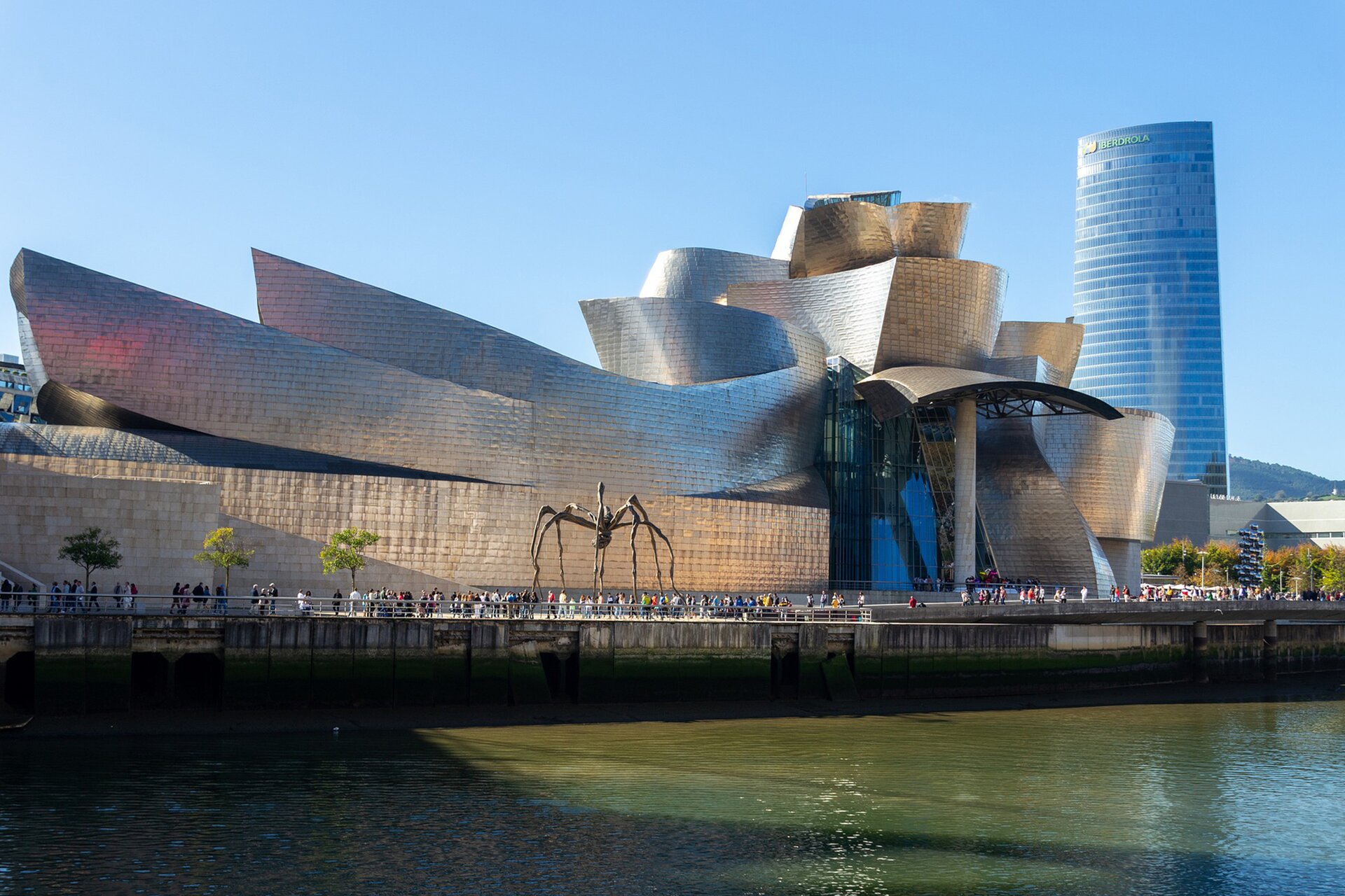Zdjęcie przedstawia Muzeum Guggenheima. Budynek z blachy i szkła o dynamicznej formie, składający się z falistych i powyginanych elementów o płynnych formach. 