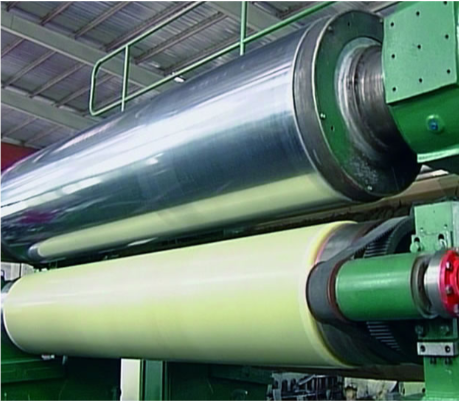 Na grafice przedstawiony jest soft kalander. Widoczne są dwie duże rolki. Ta znajdująca się wyżej jest stalowa, a ta niżej powleczona poliuretanem.