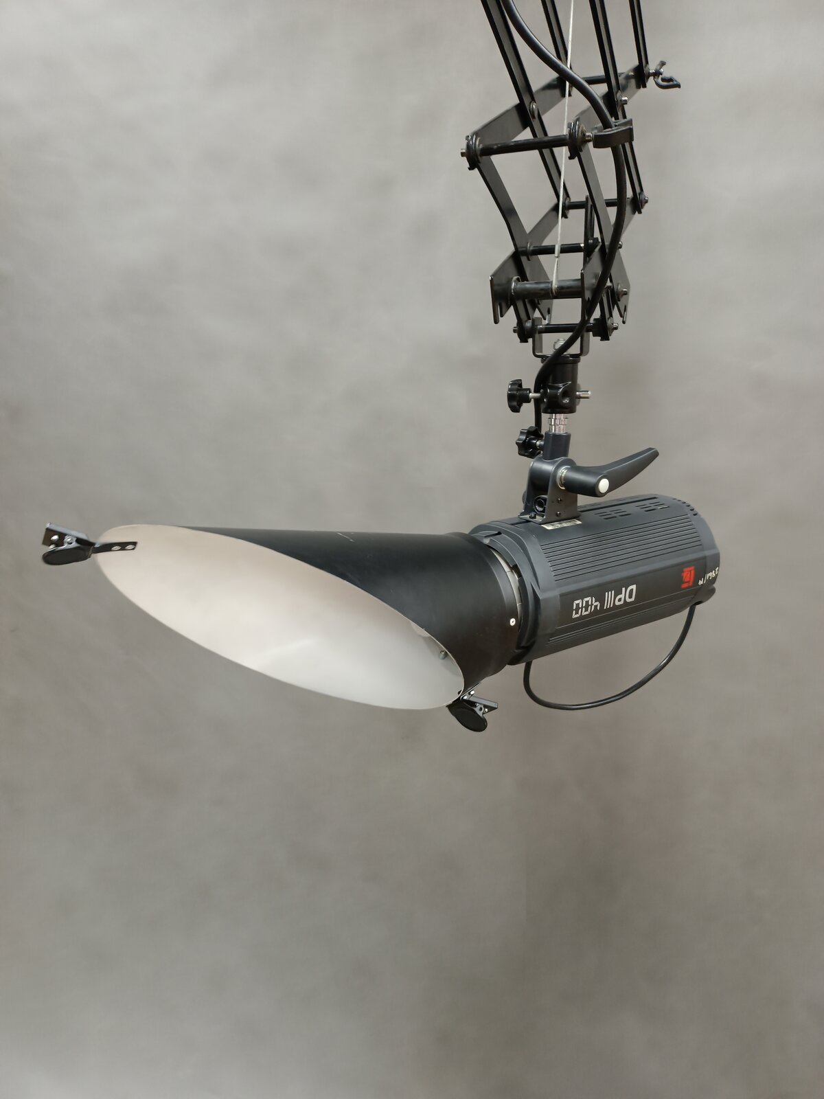 Zdjęcie przedstawia lampę studyjną z nałożoną czaszą, która jest podwieszona do wysięgnika.