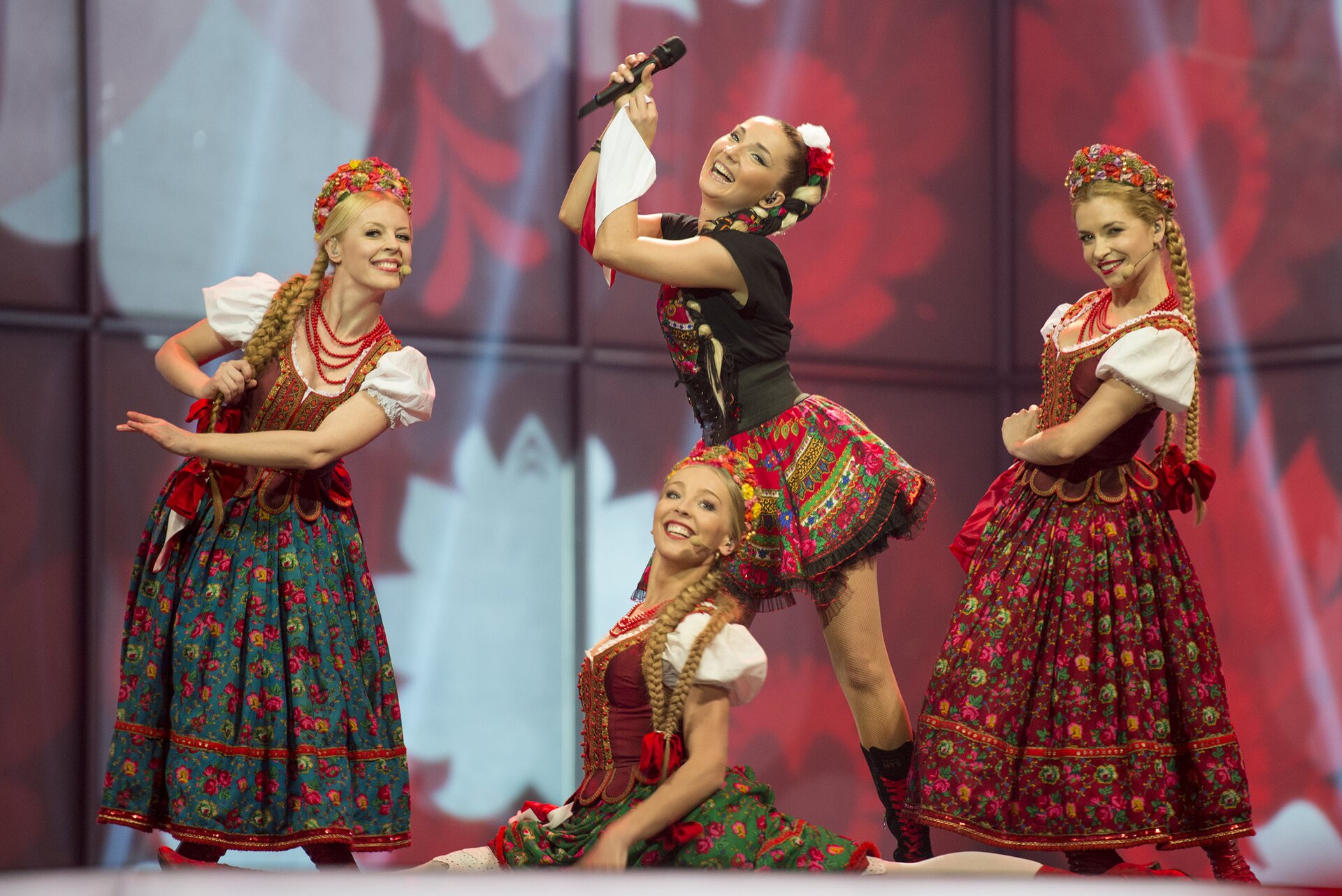Zdjęcie przedstawia scenę, na której występuje Cleo otoczona trzema tancerkami w polskich strojach ludowych.