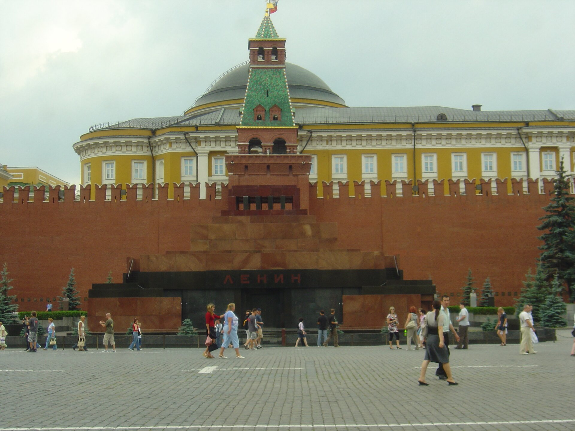 Zdjęcie przedstawia mauzoleum Lenina od strony frontowej - budowlę na planie prostokąta, podzieloną na trzy elementy: podstawę o wysokości około 3 metry, umiejscowionej ponad nią galerii oraz schodkowego zakończenia. Nad wejściem znajduje się napis w języku rosyjskim: Lenin.