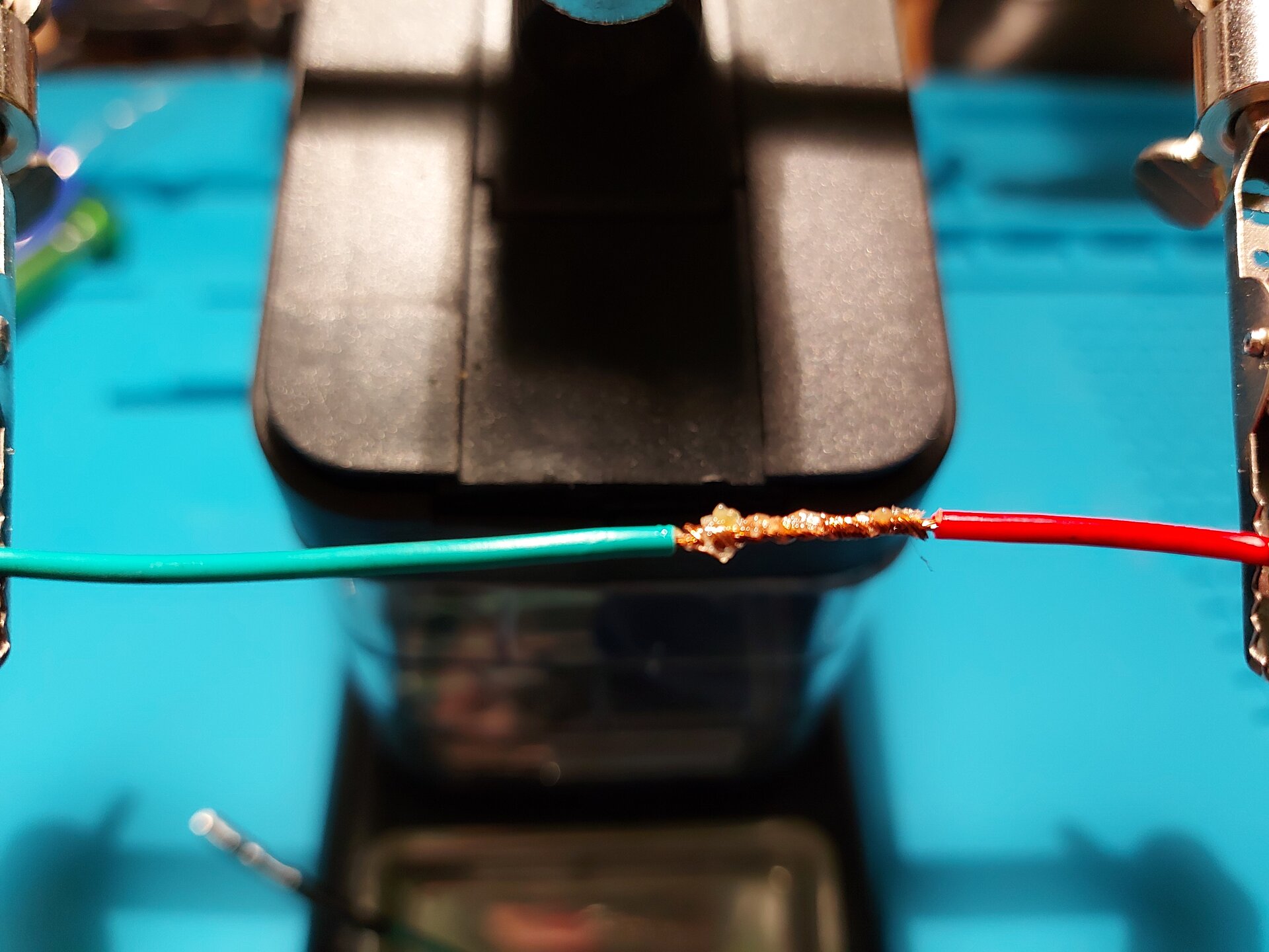 Zdjęcie przedstawia 2 przewody z usuniętą izolacją tym samym odsłaniając miedziane wnętrze, które skręcono ze sobą ustawiając miedziane zakończenia końcami przeciwnymi u podstawy następnego kabla. Nałożono na tą skrętkę pastę.