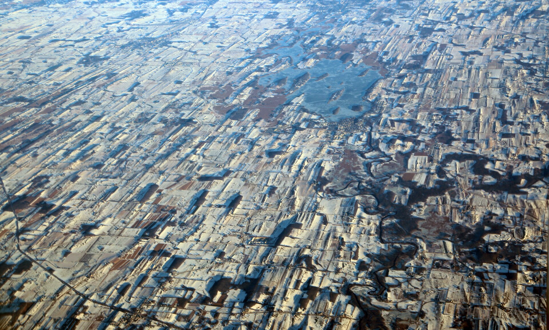 Zdjęcie satelitarne ukazuje rozległy teren. Ląd jest pokryty lodem. Formacje są wypukłe.