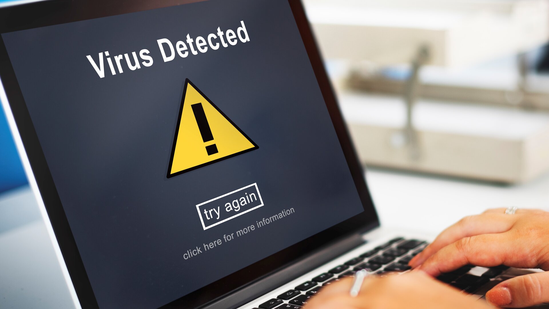 Zdjęcie przedstawia laptop, na którego ekranie widoczny jest napis: VIRUS DETECTED oraz znak żółtego trójkąta z wykrzyknikiem, pod spodem widoczny napis TRY AGAIN.