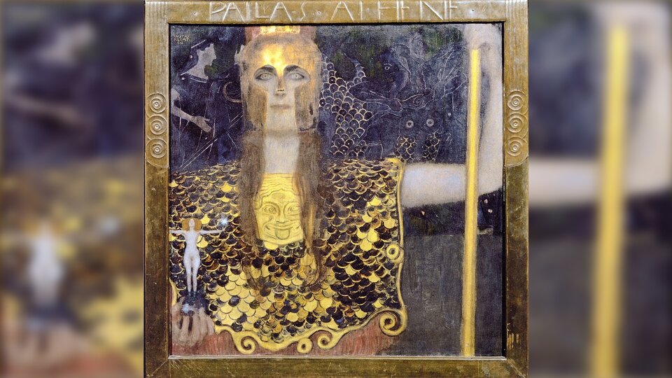 Ilustracja przedstawia popiersie kobiety w złotej zbroi. To Atena. Jej zbroja zrobiona jest z dziesiątków okrągłych płytek, na głowie ma złoty hełm z ochroną na policzki i nos. Widać tylko oczy, usta i brodę. Spod hełmu wystają długie blond włosy. Lewą rękę opiera na złotej dzidzie, w prawej trzyma figurkę nagiej kobiety, która ma rozłożone na boki ręce. W tle, prawie niewidoczna, sowa i dwaj wojownicy.