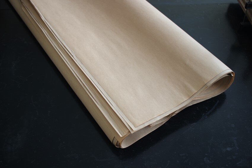 Zdjęcie przedstawia kilka zwiniętych we wstęgę arkuszy papieru niebielonego, workowego.