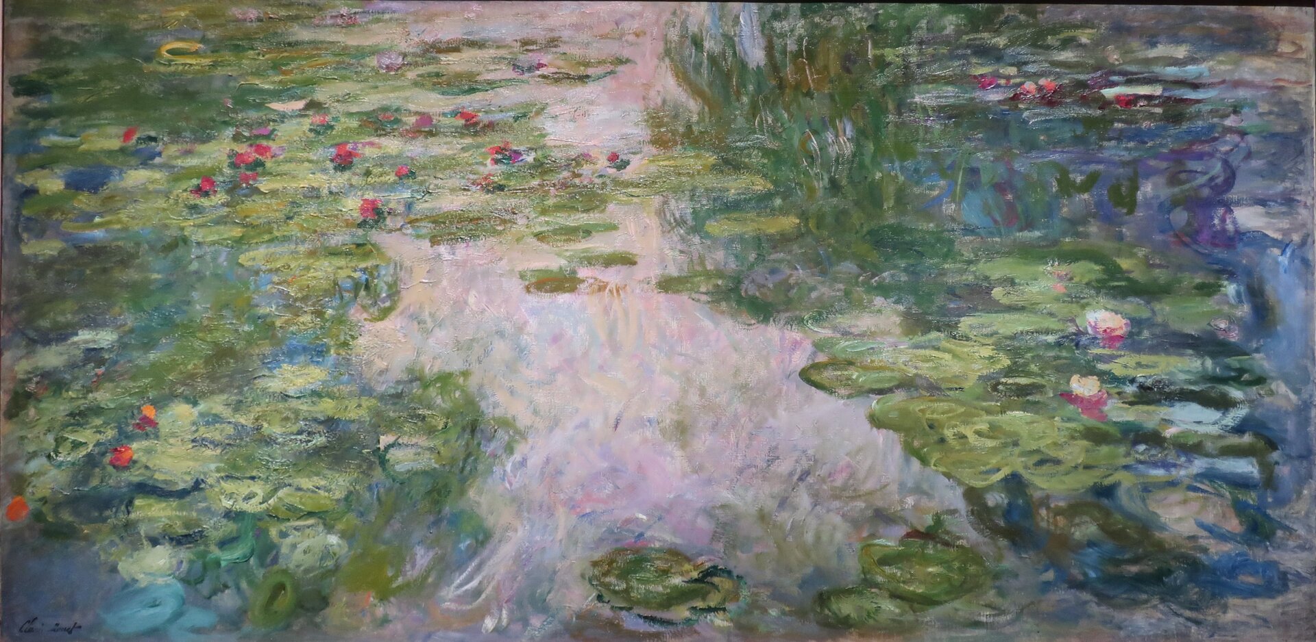 Obraz autorstwa Claude Monet, pod tytułem „Lilie wodne”. Obraz przedstawia czerwone lilie wodne. W niebieskiej tafli wody odbija się jasne niebo.