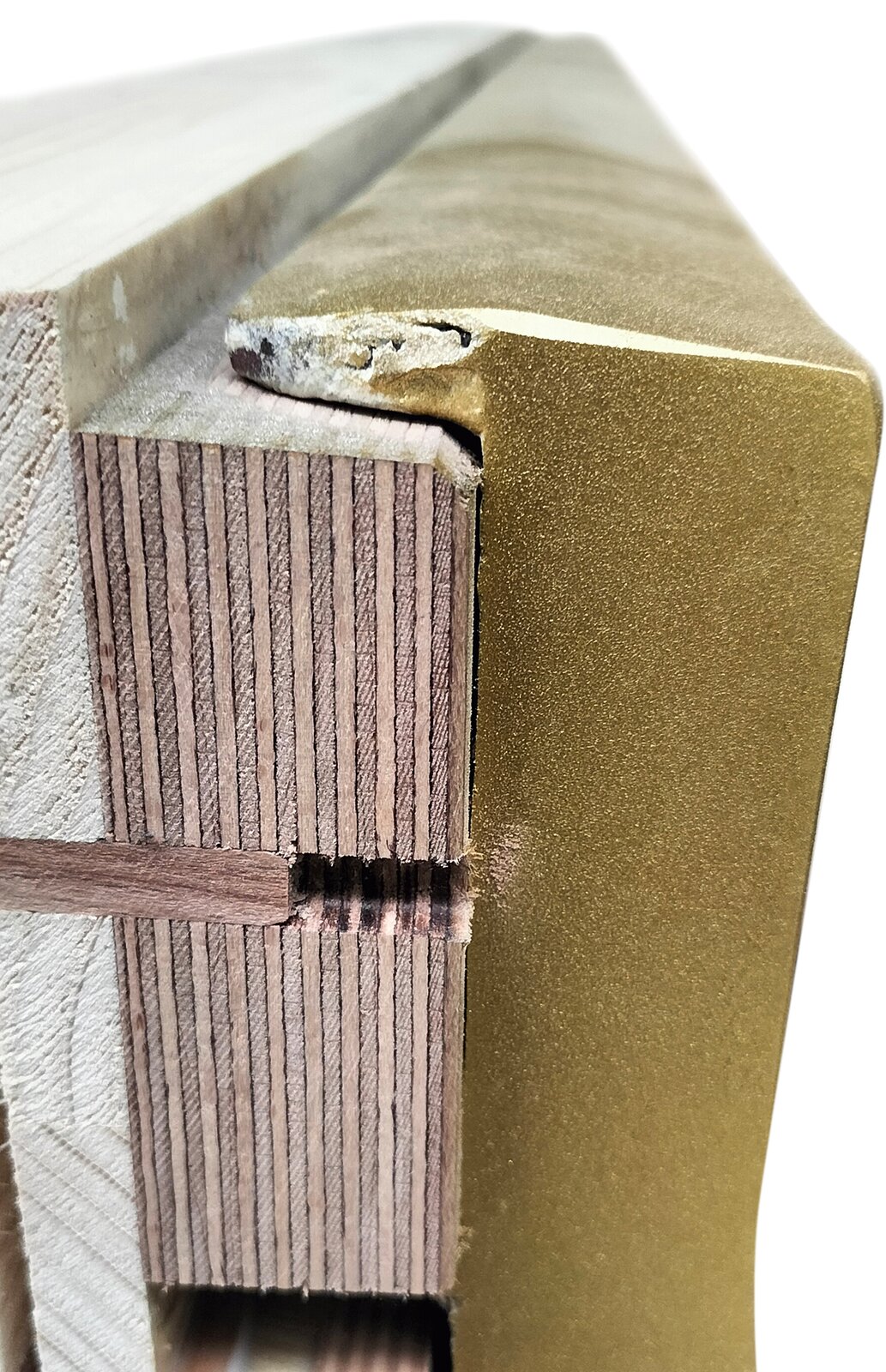 Zdjęcie przedstawia fragment strojnicy i ramy żeliwnej pianina z boku. Strojnica jest wykonana ze sklejki w kolorze jasno i ciemnobrązowym, sklejonej klejem Titenbond. Rama żeliwna po prawej jest w kolorze starego złota.