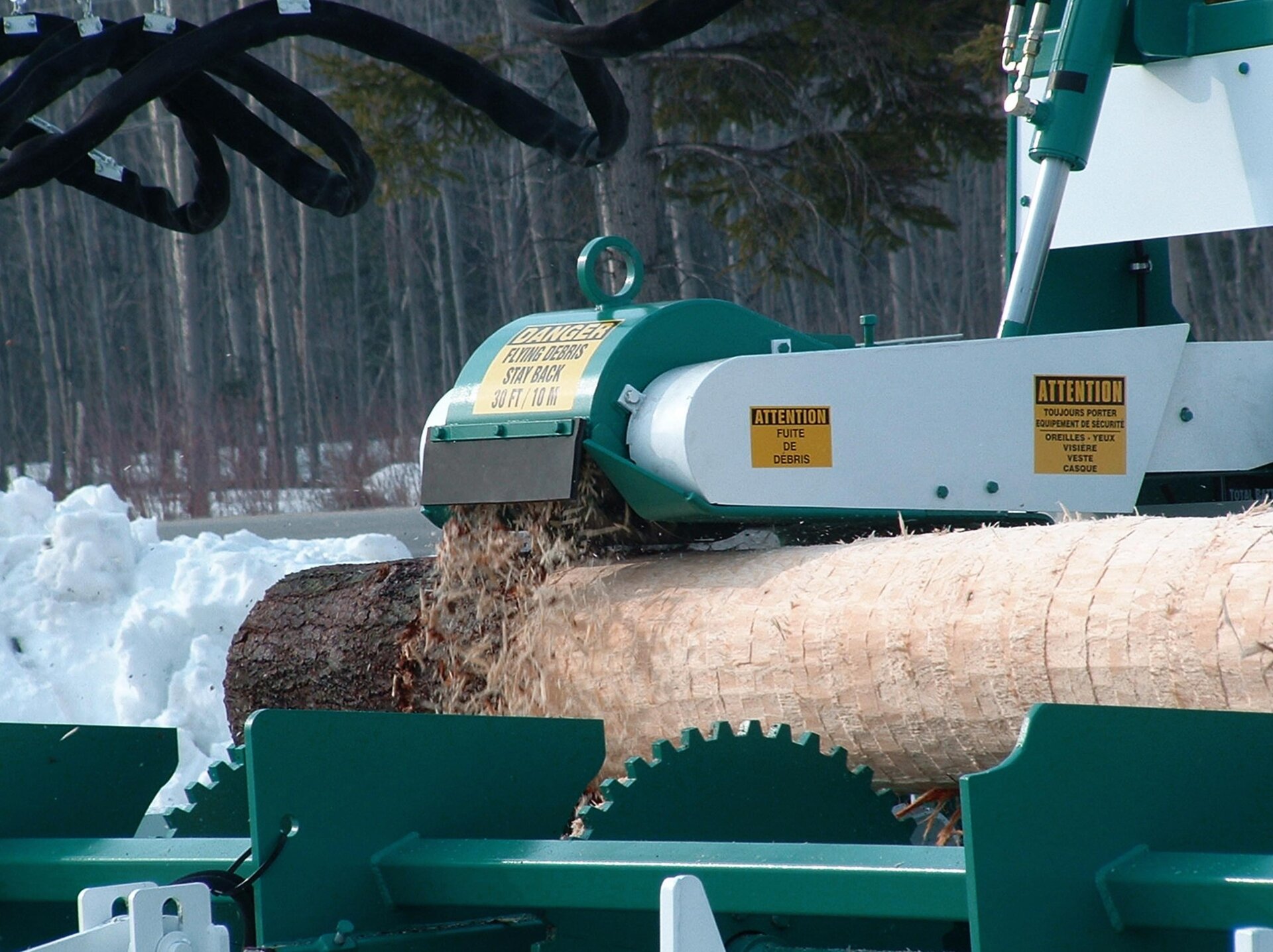 Zdjęcie przedstawia proces korowania mechanicznego. Pień ściętego drzewa umieszczony został w specjalnej maszynie, która skrawa pokrywającą go korę. 