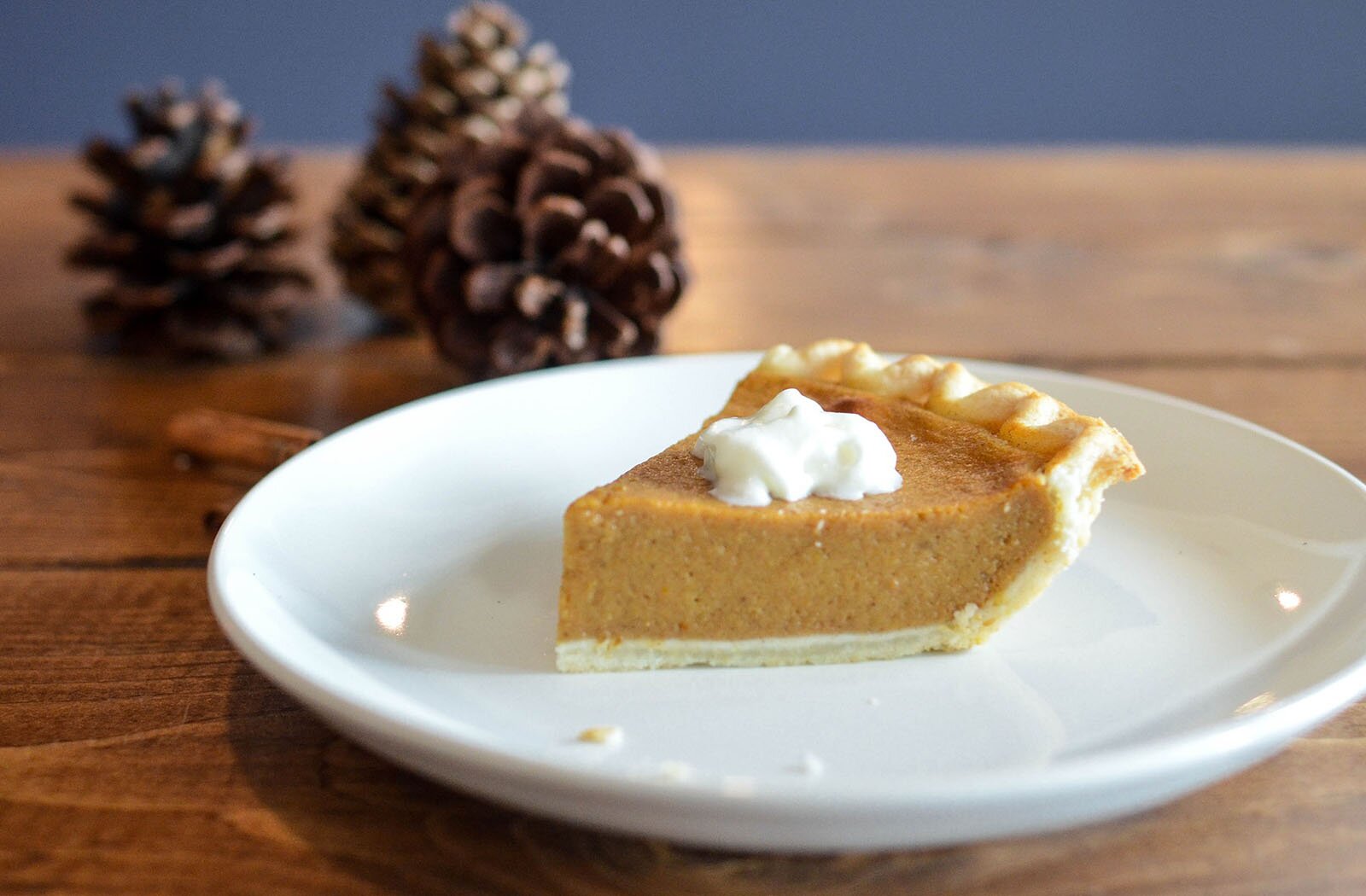 Zdjęcie przedstawia kawałek dyniowego placka ułożonego na białym talerzu.