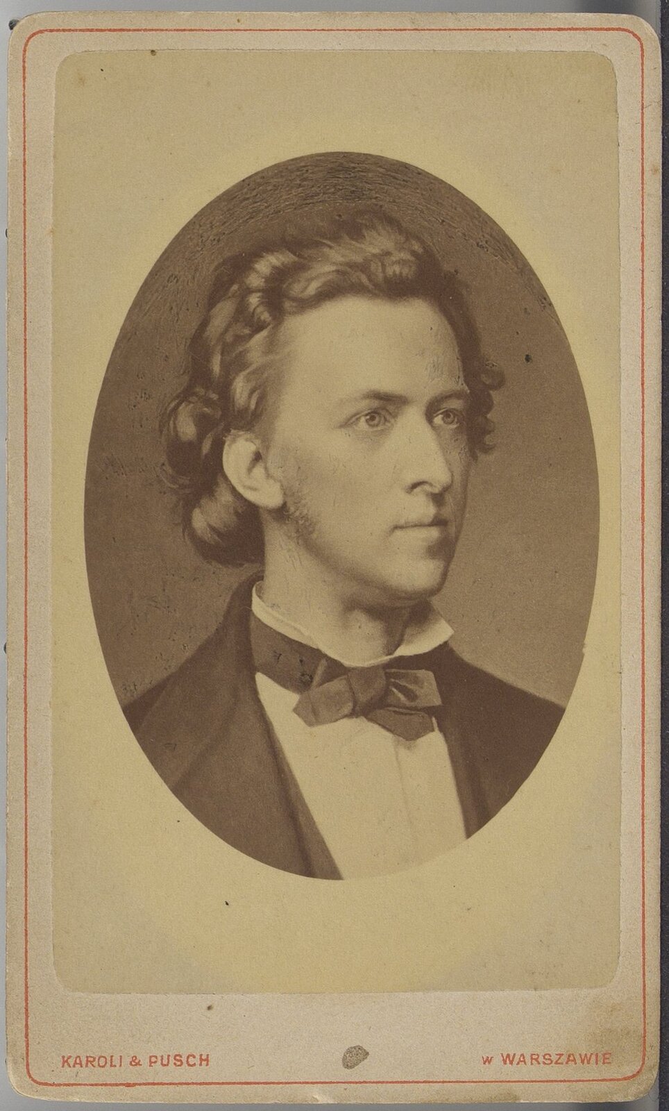 Na ilustracji znajduje się mężczyzna ubrany w marynarkę, białą koszulę oraz muszkę. Mężczyzna ma kręcone włosy. Ilustracja jest czarno‑biała.