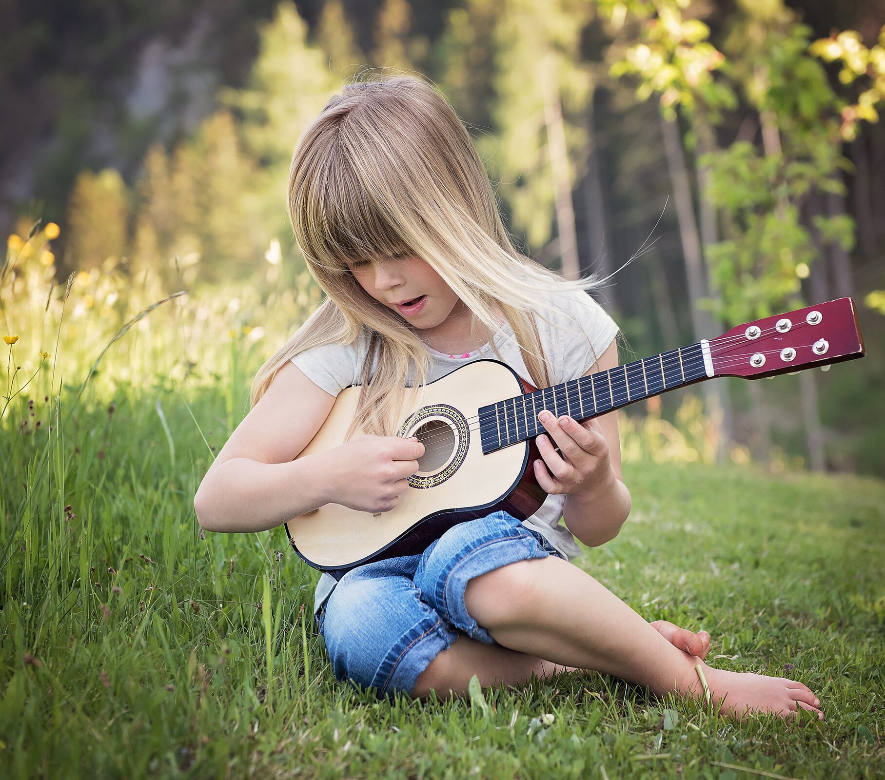 Ilustracja przedstawia dziewczynkę grającą na gitarze