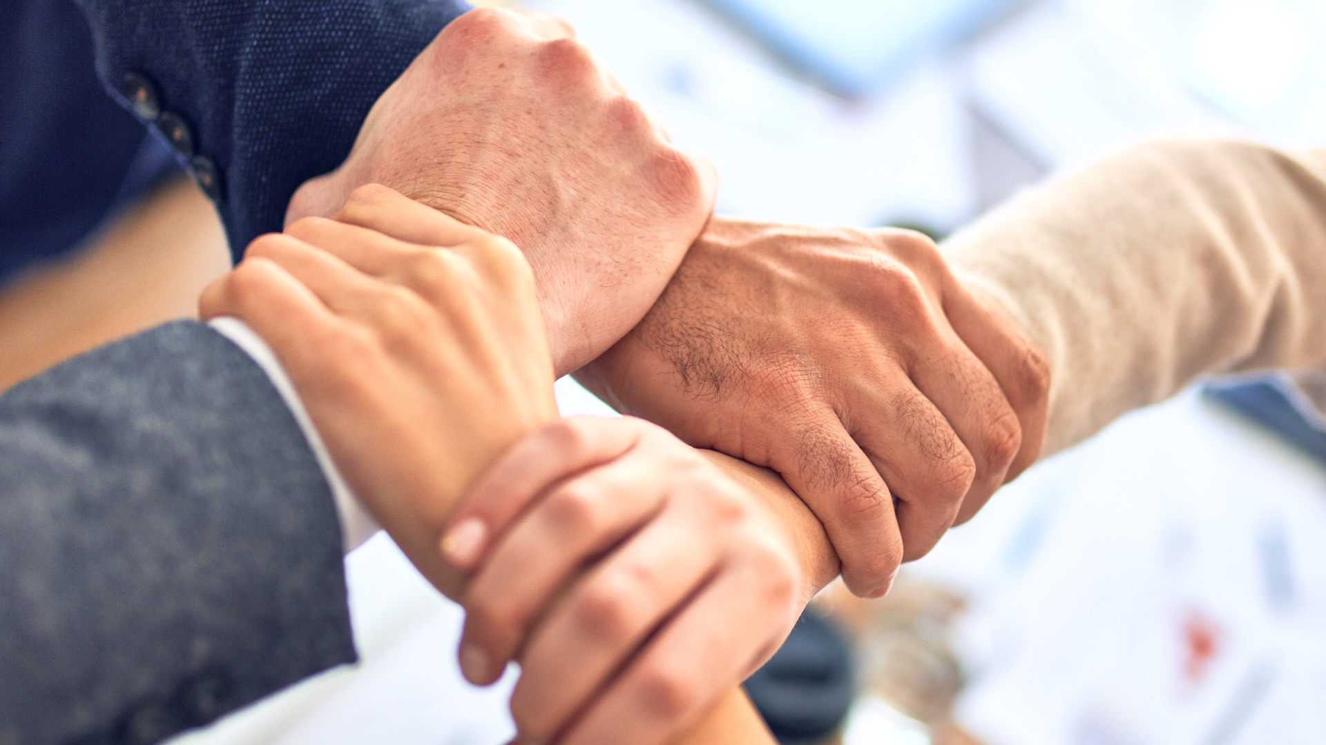 Zdjęcie przedstawia splecione ręce osób w geście jedności.