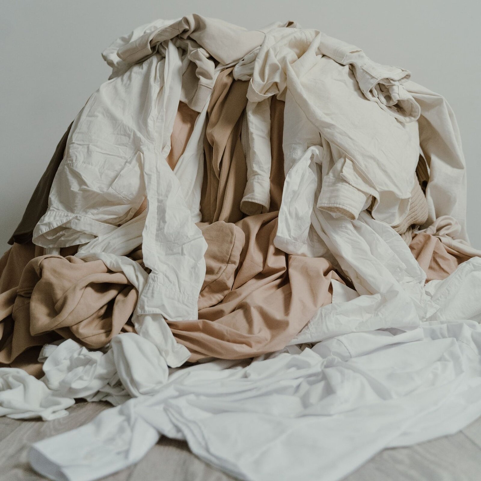 Widoczna jest fotografia. Przedstawia stos białych i beżowych ubrań.