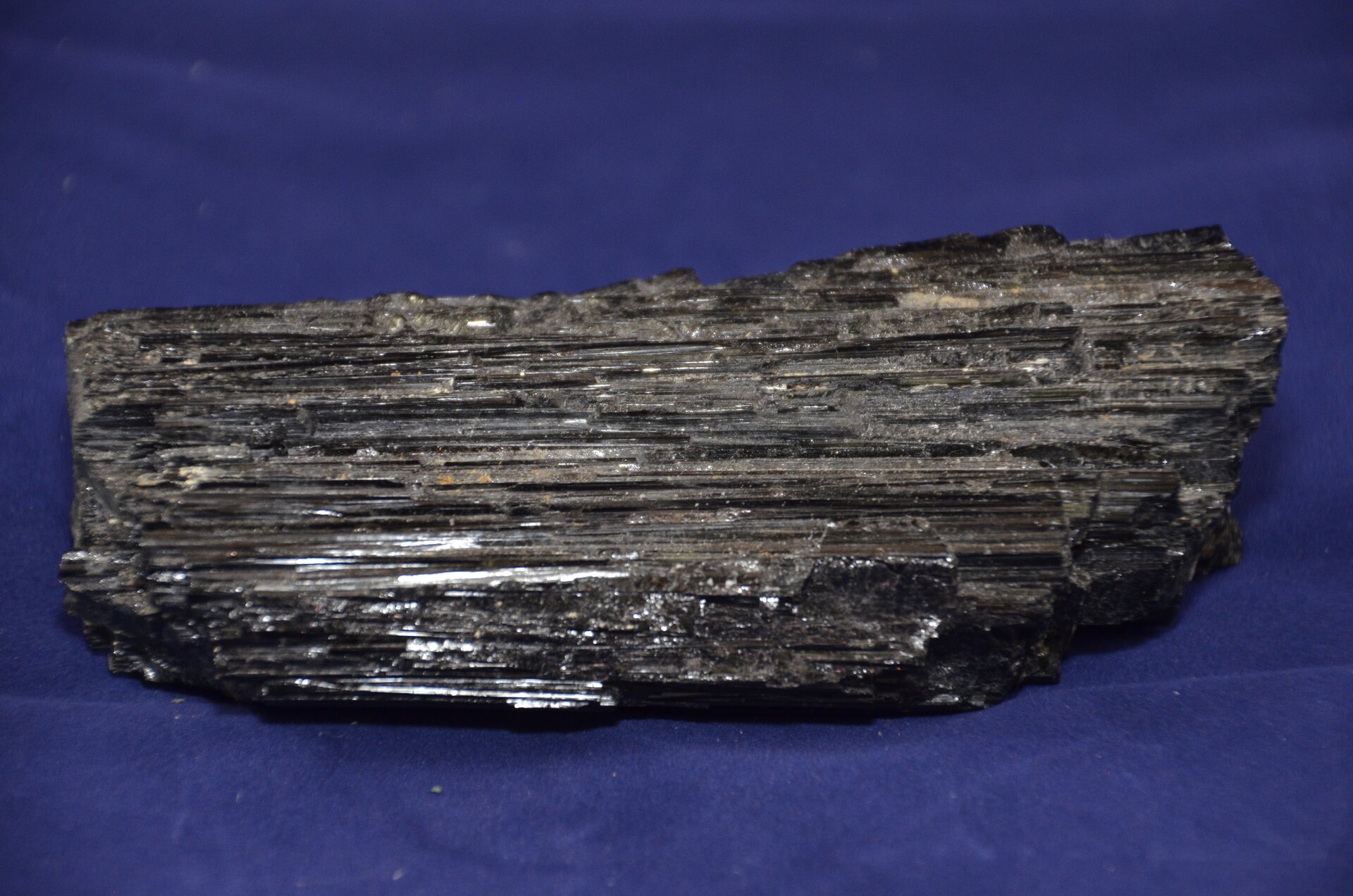 Na zdjęciu znajduje się minerał z charakterystycznymi zbrużdżeniami, zgodnymi z wydłużeniem słupów. 