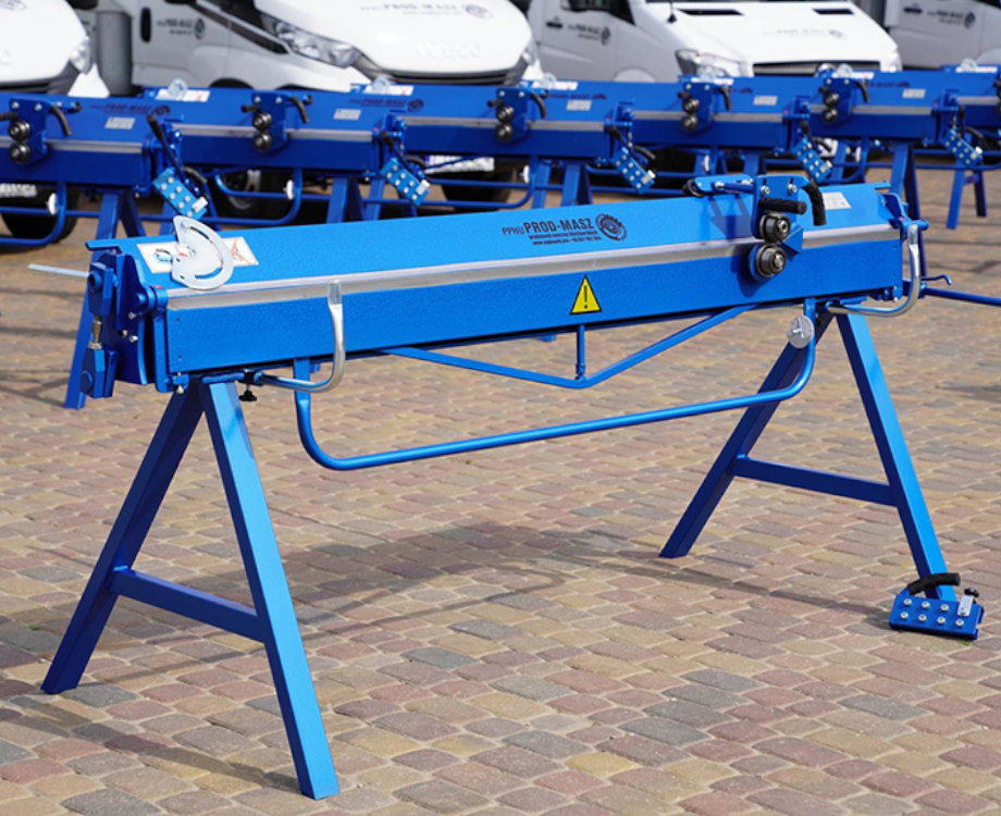 Na zdjęciu widoczna jest krawędziarka. Urządzenie składa się z poziomej belki z uchwytem osadzonej na dwóch trójkątnych nogach.