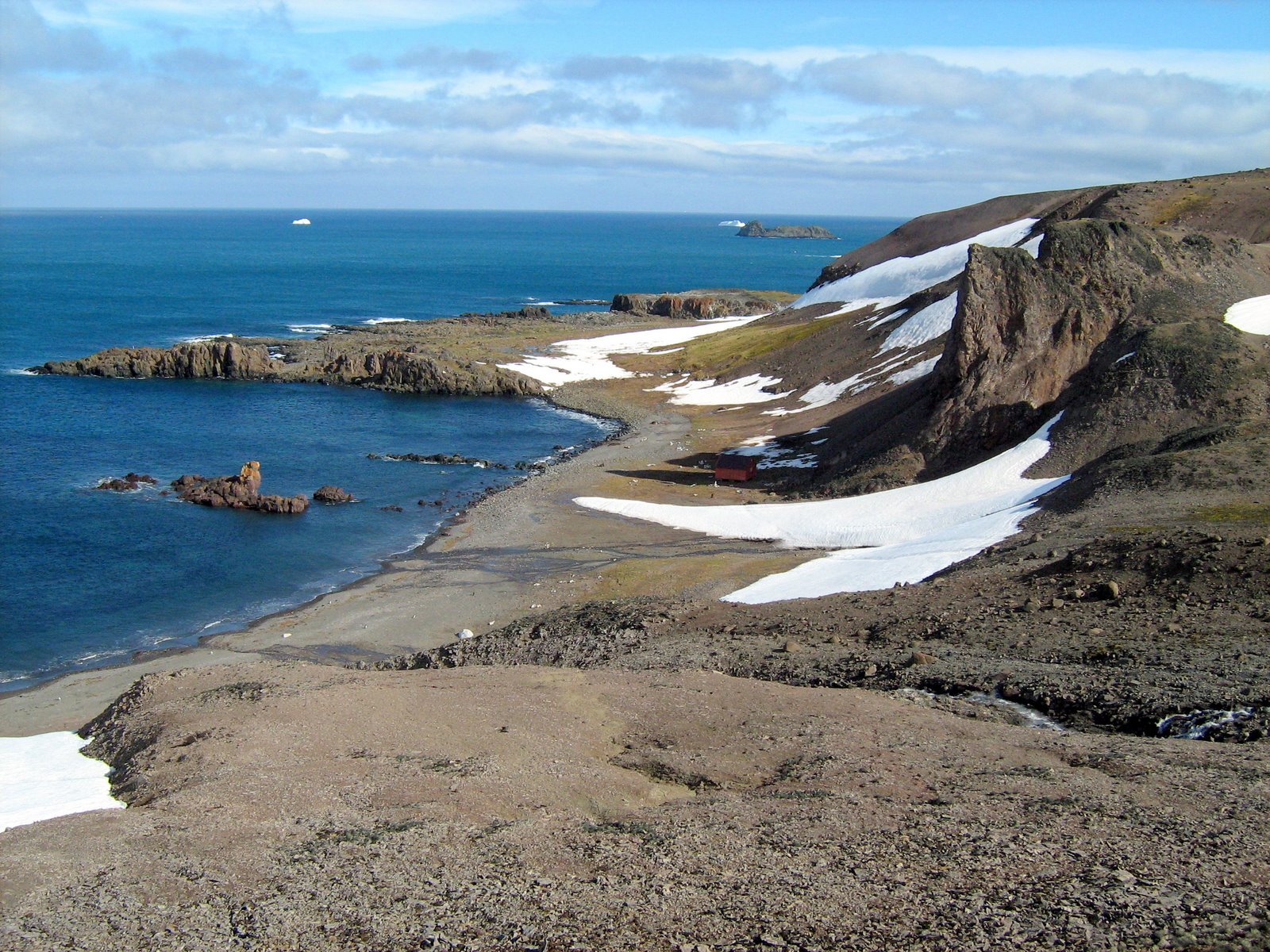 Fotografia wybrzeża składającego się z dość stromych, w większości niepokrytych roślinnością stoków.
