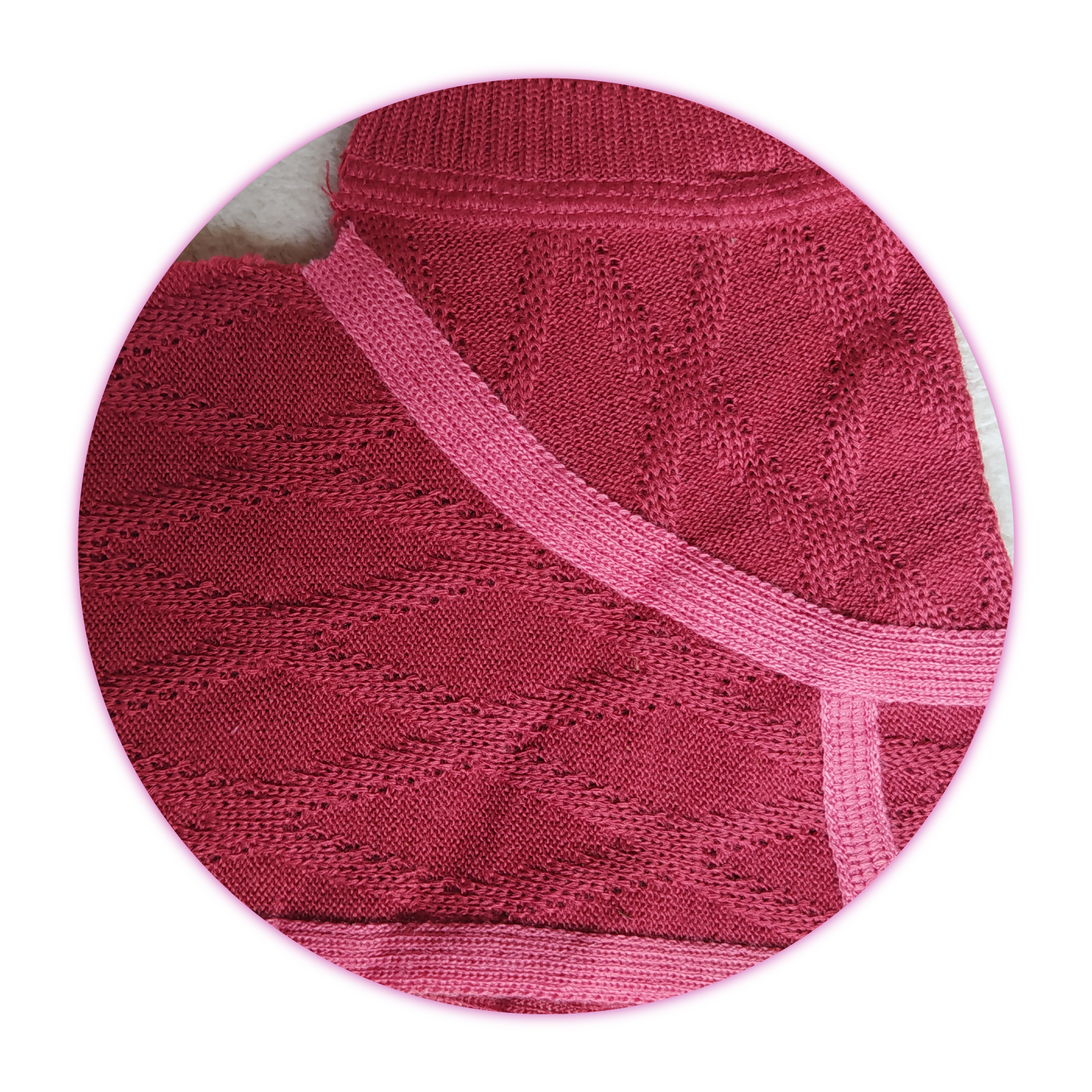 Zdjęcie przedstawia fragment dzianinowego wyrobu odzieżowego z krótkimi rękawami w ciemnoróżowym kolorze z jaśniejszymi lamówkami.