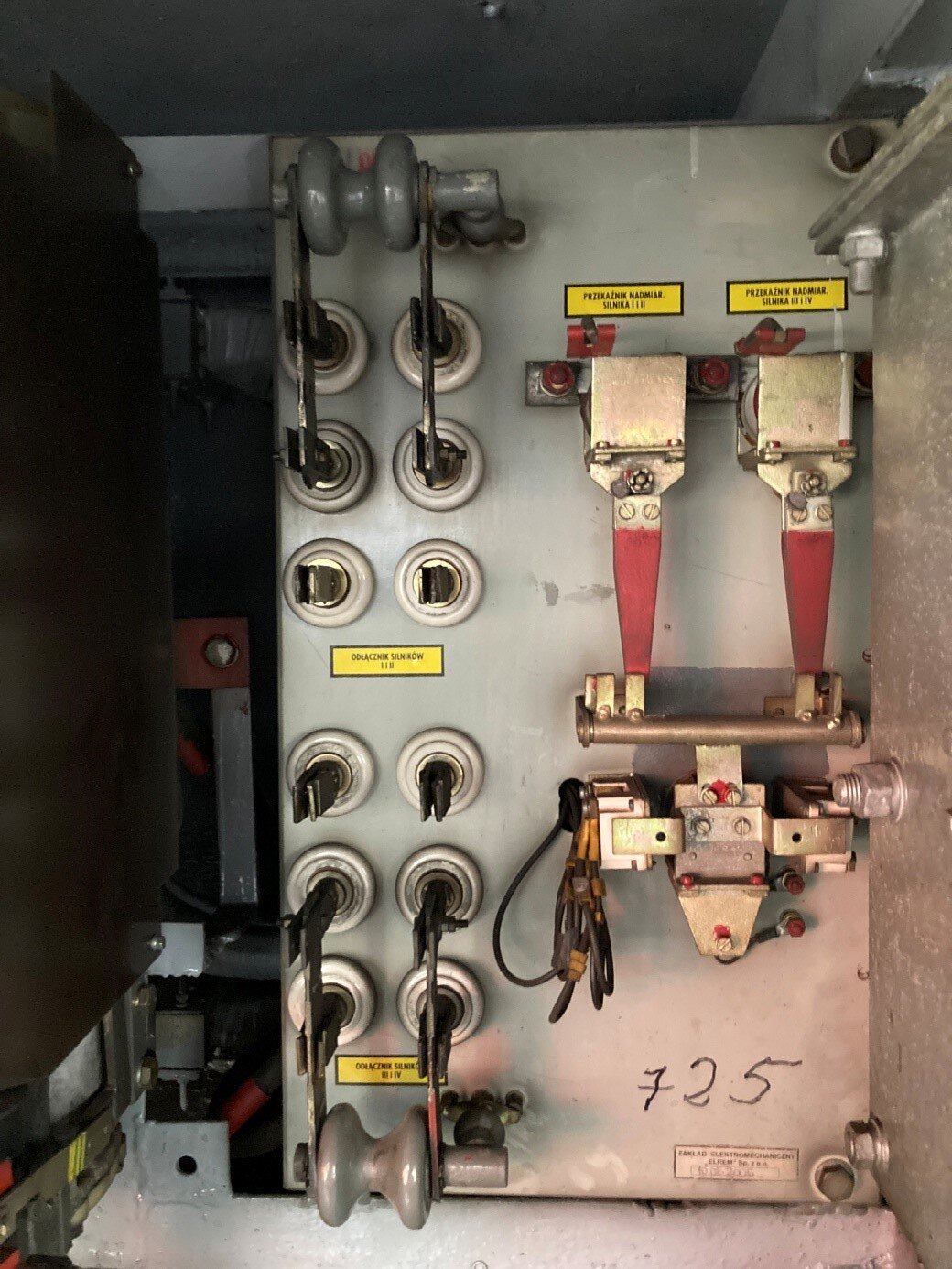 Na zdjęciu przedstawione są odłączniki silników trakcyjnych. Żółte tabliczki na panelu informują do czego służą dane odłączniki. Po lewej stronie panelu znajdują się dwa zestawy styków nieruchomych, ustawionych w dwóch kolumnach po trzy. Do środkowych dwóch styków w obu zestawach przykręcone są blaszki połączone ze sobą na końcach izolatorem. Wychylone są one na zewnątrz tak, że stykają się z dwoma stykami skrajnie zewnętrznymi. Wewnętrzne styki pozostają niepołączone. W prawej połowie panelu znajdują się dwa przekaźniki nadmiarowe silników.