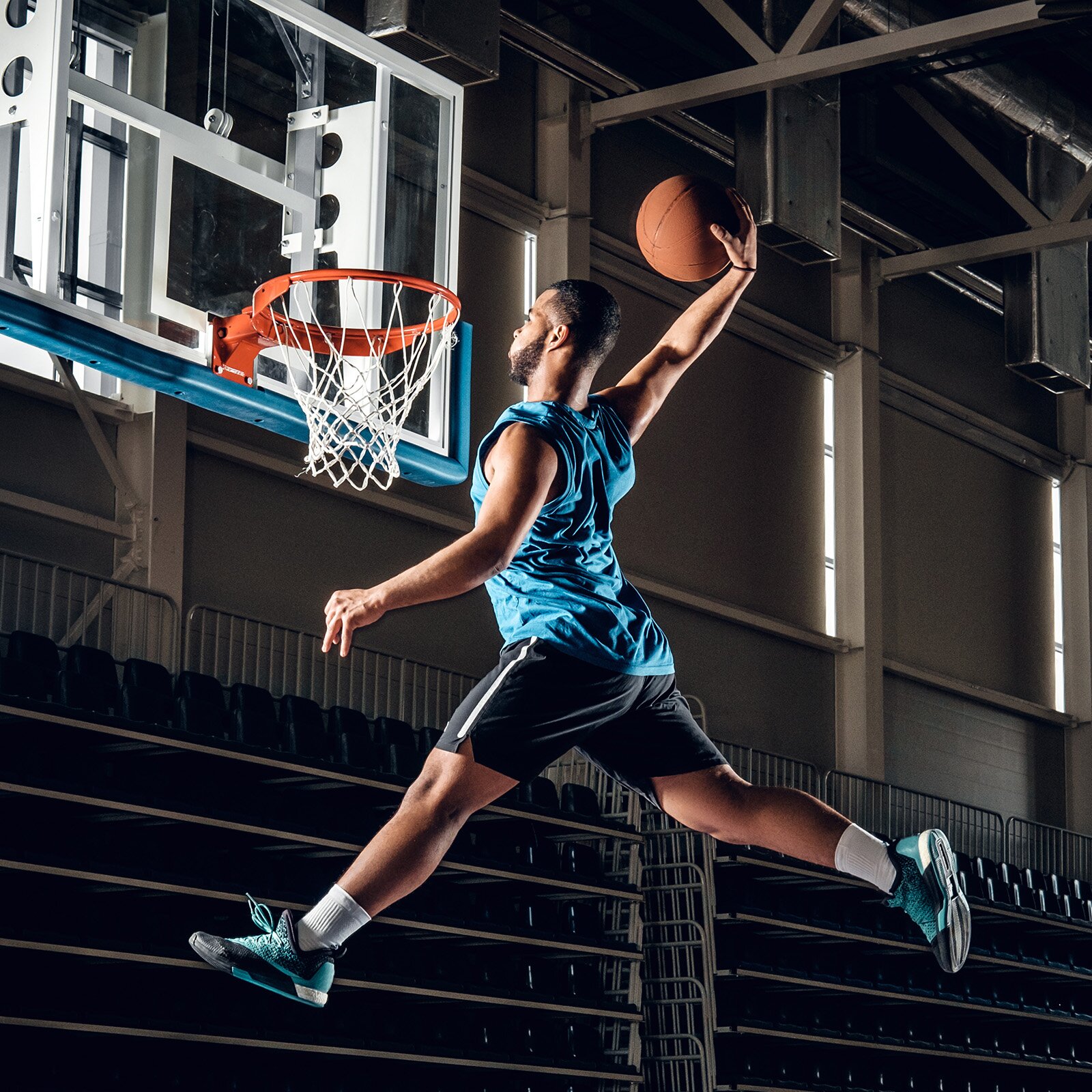 Zdjęcie przedstawia nastolatka w stroju sportowym wrzucającego piłkę do kosza. 