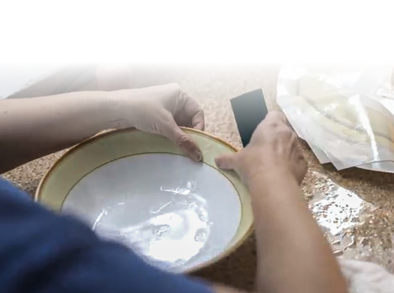 Zdjęcie ukazuje ręce pracownika produkcji, który trzyma w nich głęboki talerz ze zdobionym rantem.