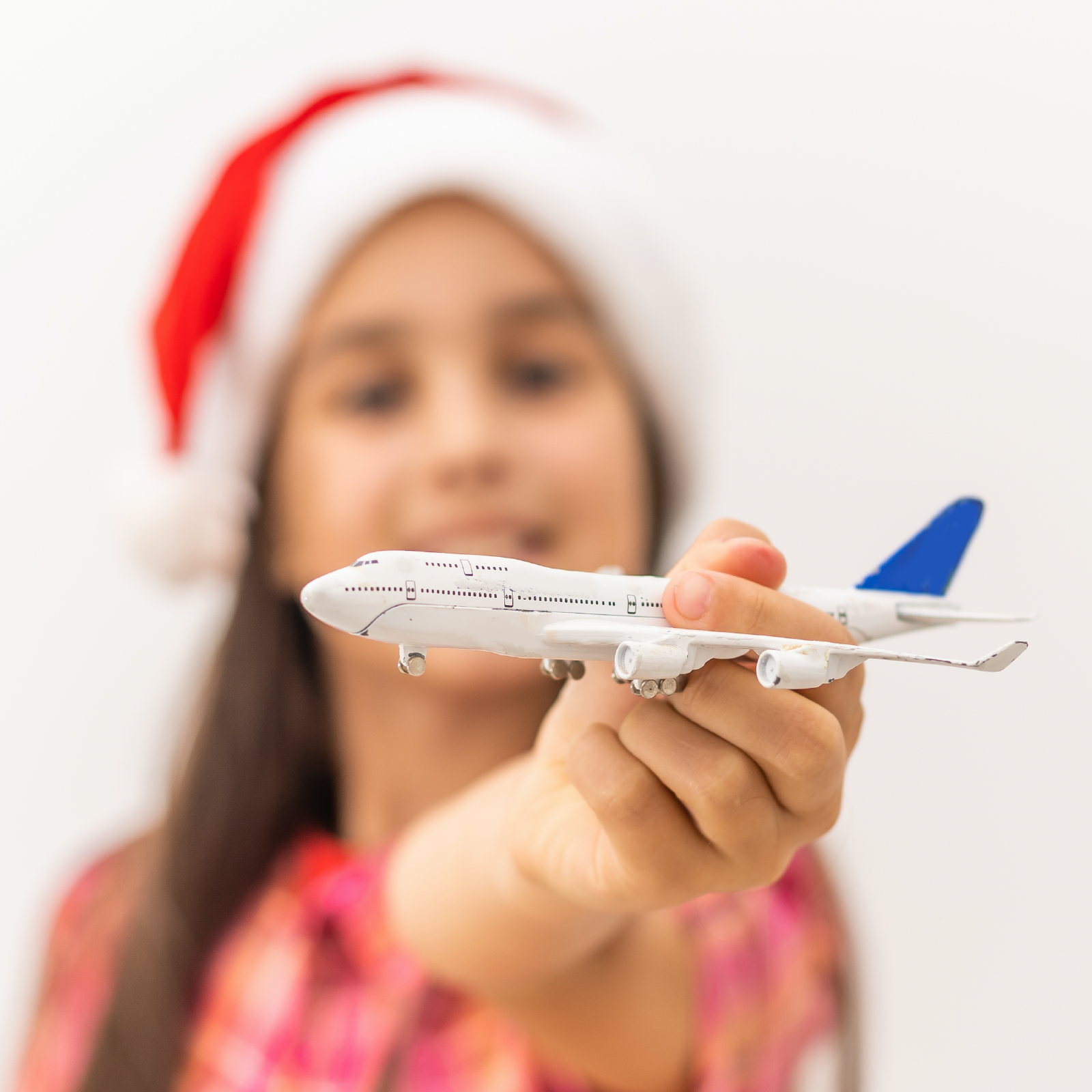 Ilustracja ukazuje dziewczynkę, która w dłoni trzyma zabawkowy samolot pasażerski. 