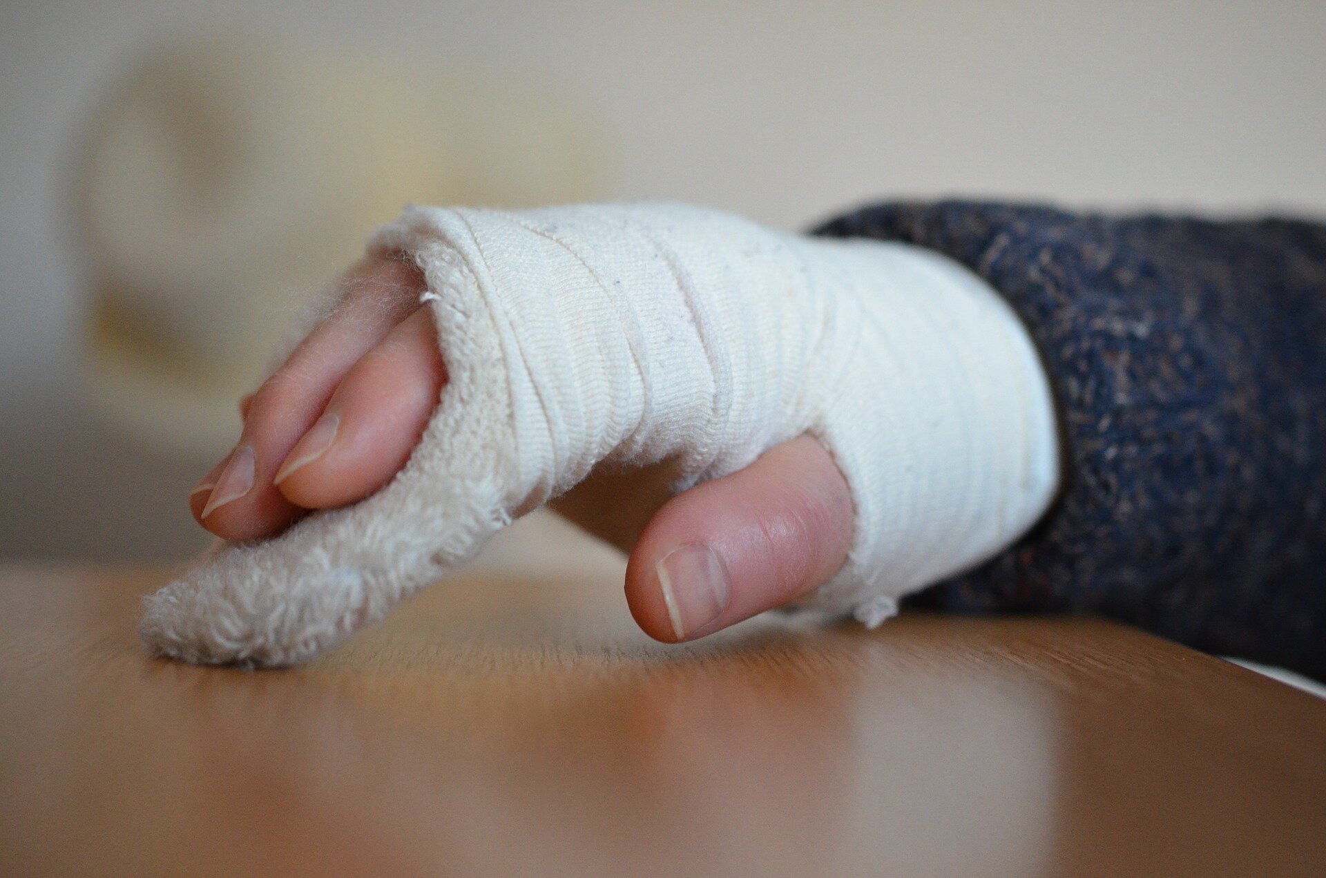 Fotografia przedstawia dłoń umieszczoną w gipsie medycznym owiniętą bandażem.