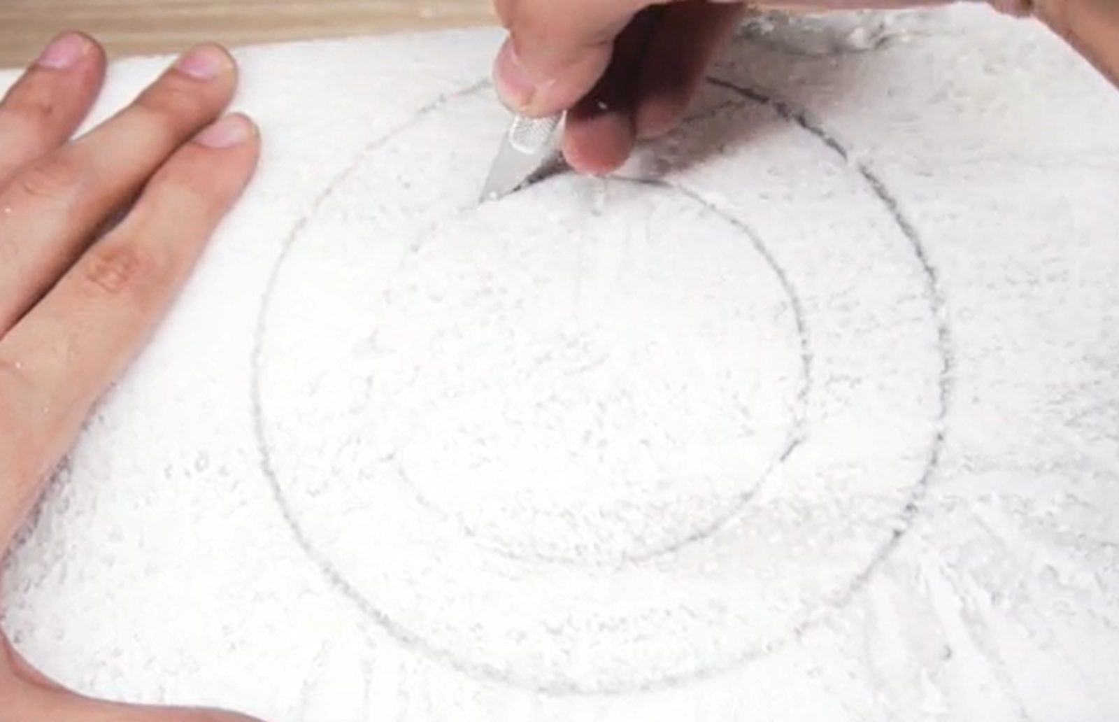 Na zdjęciu ktoś wycina okręgi w styropianie.