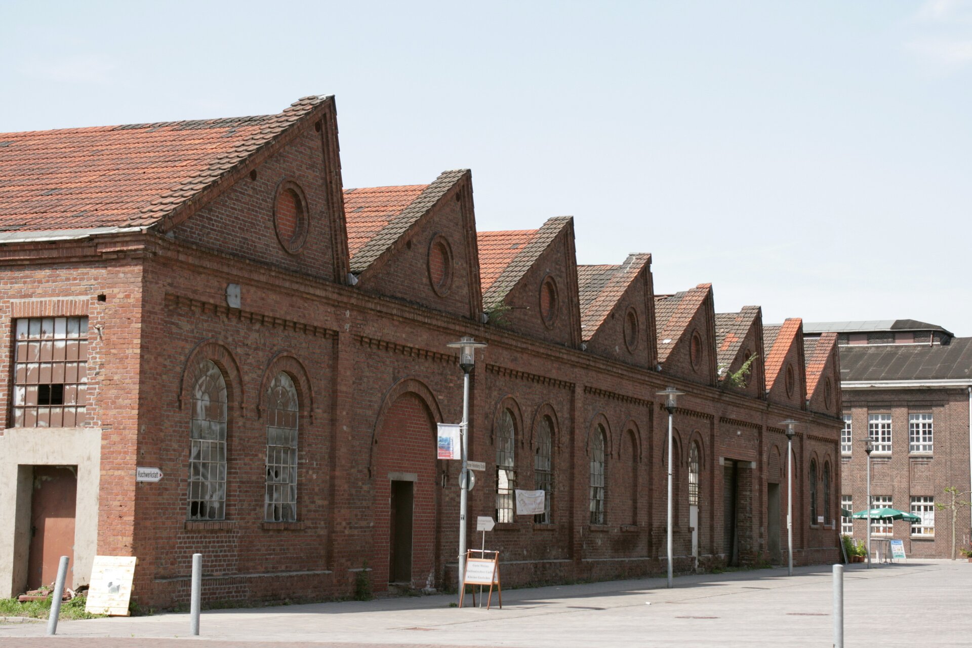 Zdjęcie przedstawia budynek z dachem pilastym. Budynek jest z czerwonej cegły. Na dachu znajduje się czerwona dachówka. 