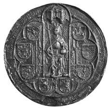 Na zdjeciu znajduje się srebrna moneta. Przedstawia na Kazimierza czwartego Jagiellończyka siedzącego na tronie. Trzyma berło i królewskie jabłko. Jest on otoczony licznymi herbami.