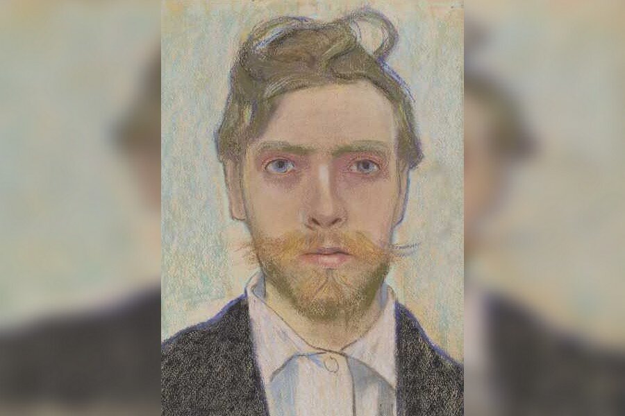 Obraz przedstawia twarz młodego mężczyzny. Ma lekko zmierzwione, średniej długości włosy. Jego pociągłą twarz ozdabia zarost - niewielka broda i wąsy. Mężczyzna jest ubrany w koszulę i marynarkę.